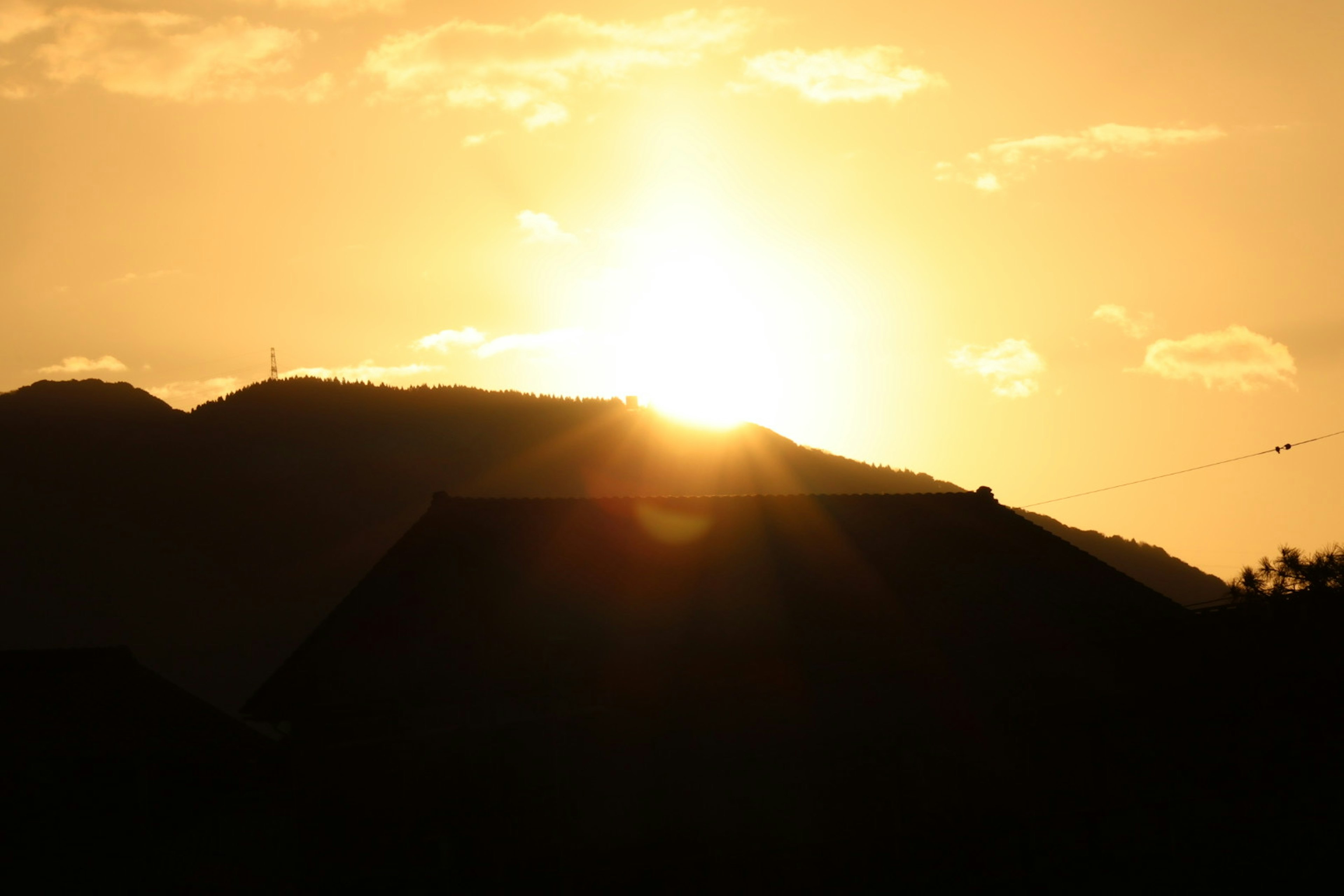 山の上に沈む夕日シルエットと雲のある風景