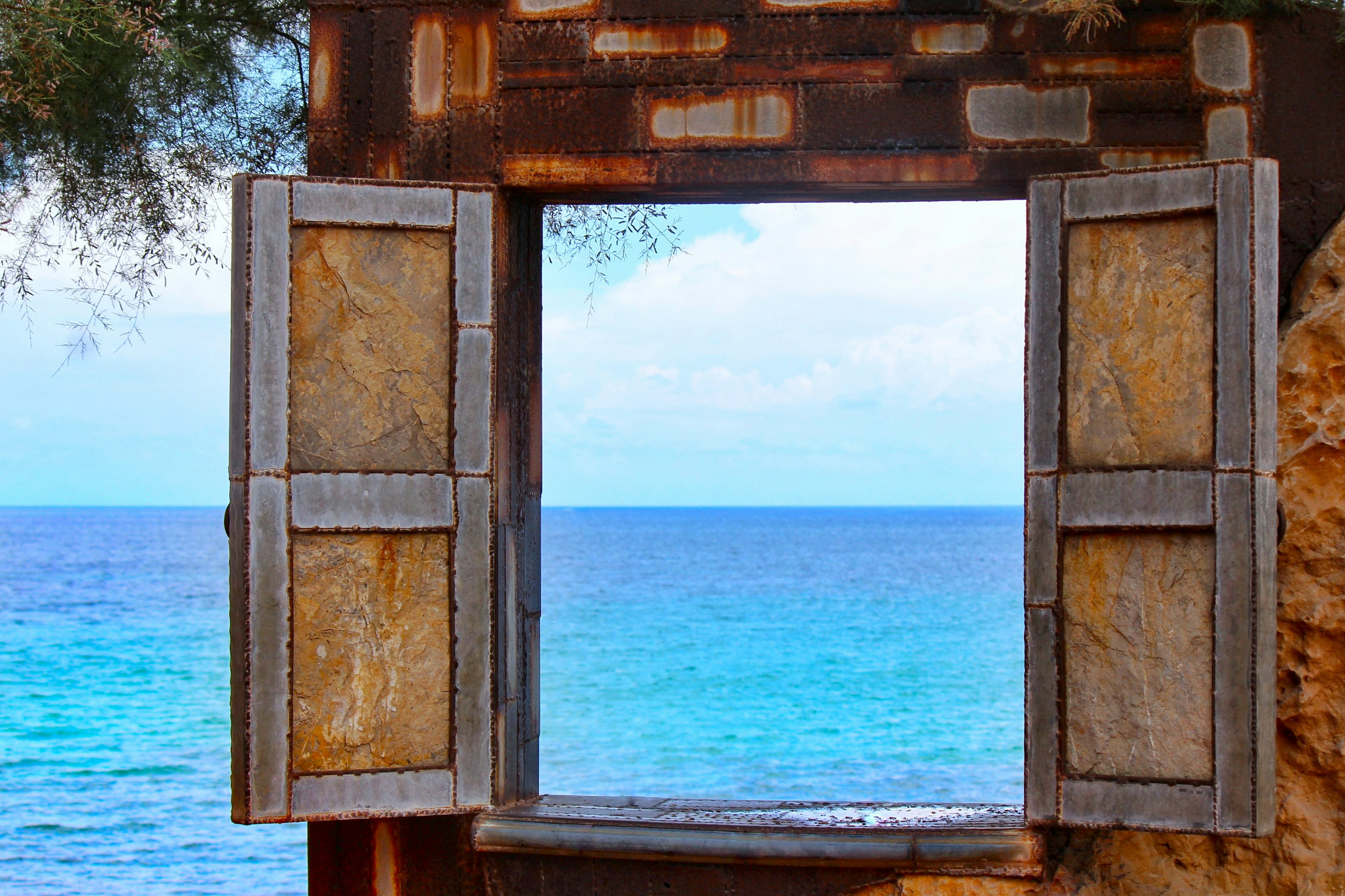 Old window frame overlooking a blue sea