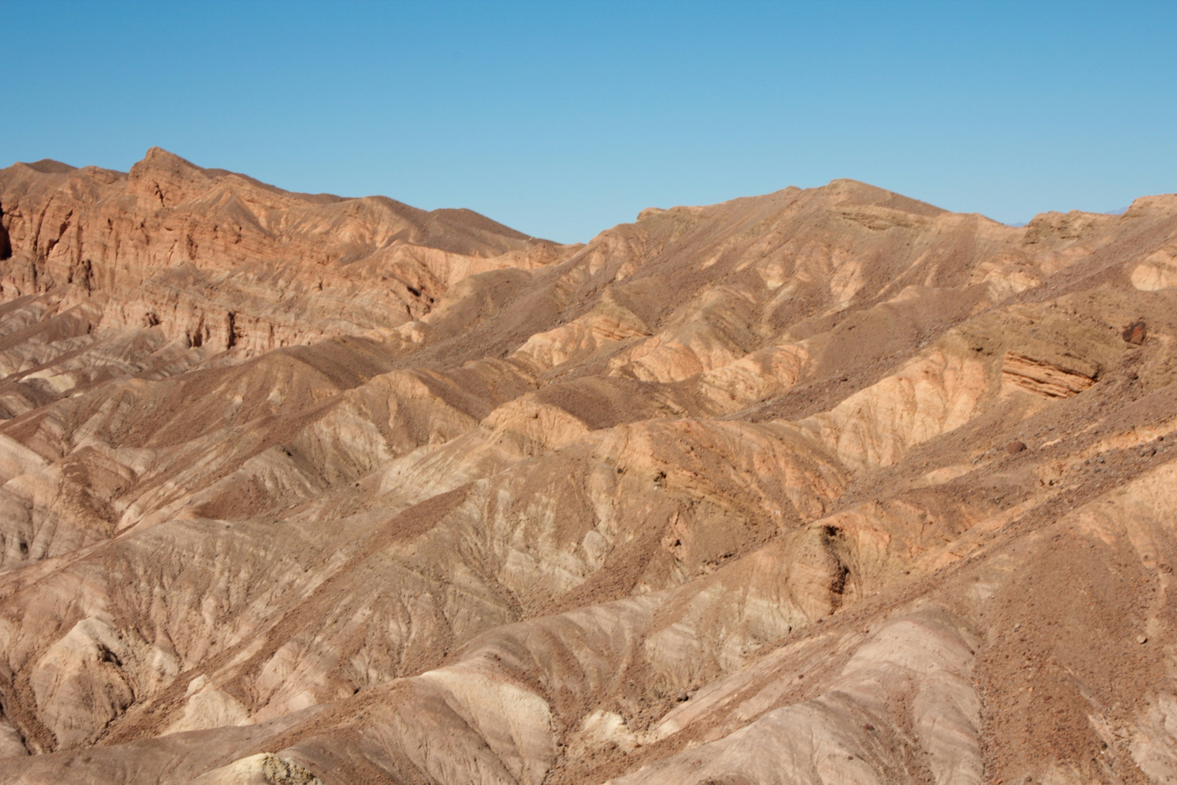 Paysage de montagnes sèches avec des couches colorées sous un ciel bleu clair