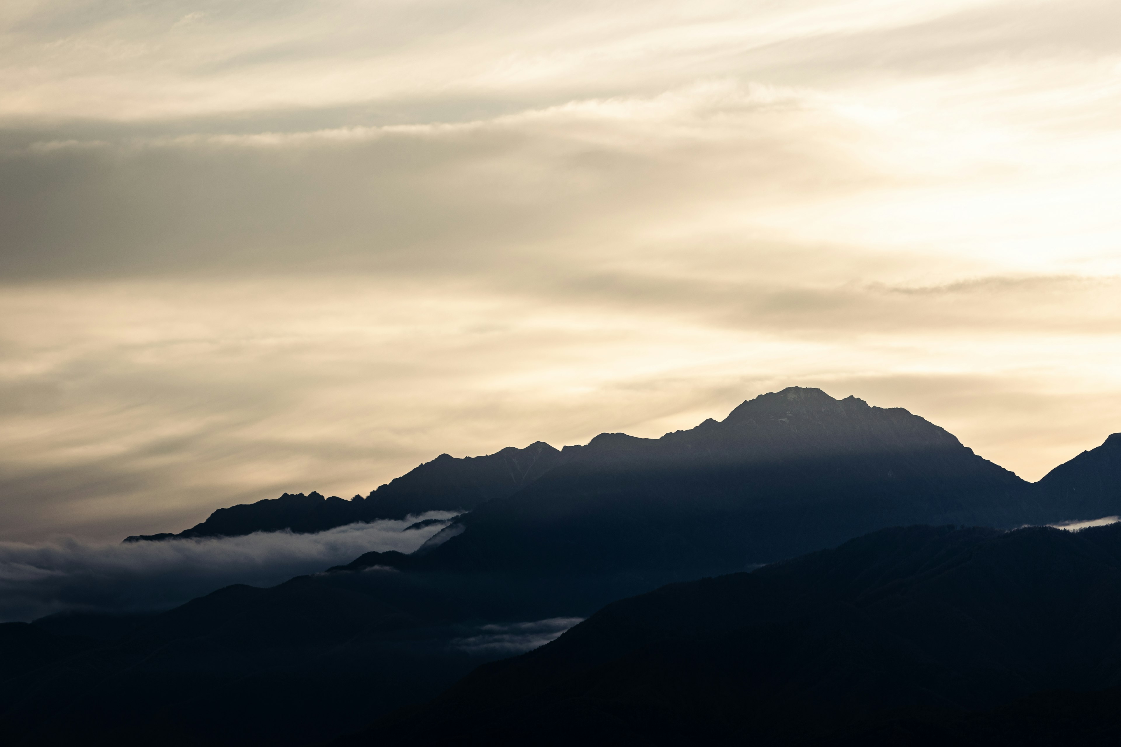 Silhouette di montagne con nuvole contro un cielo crepuscolare