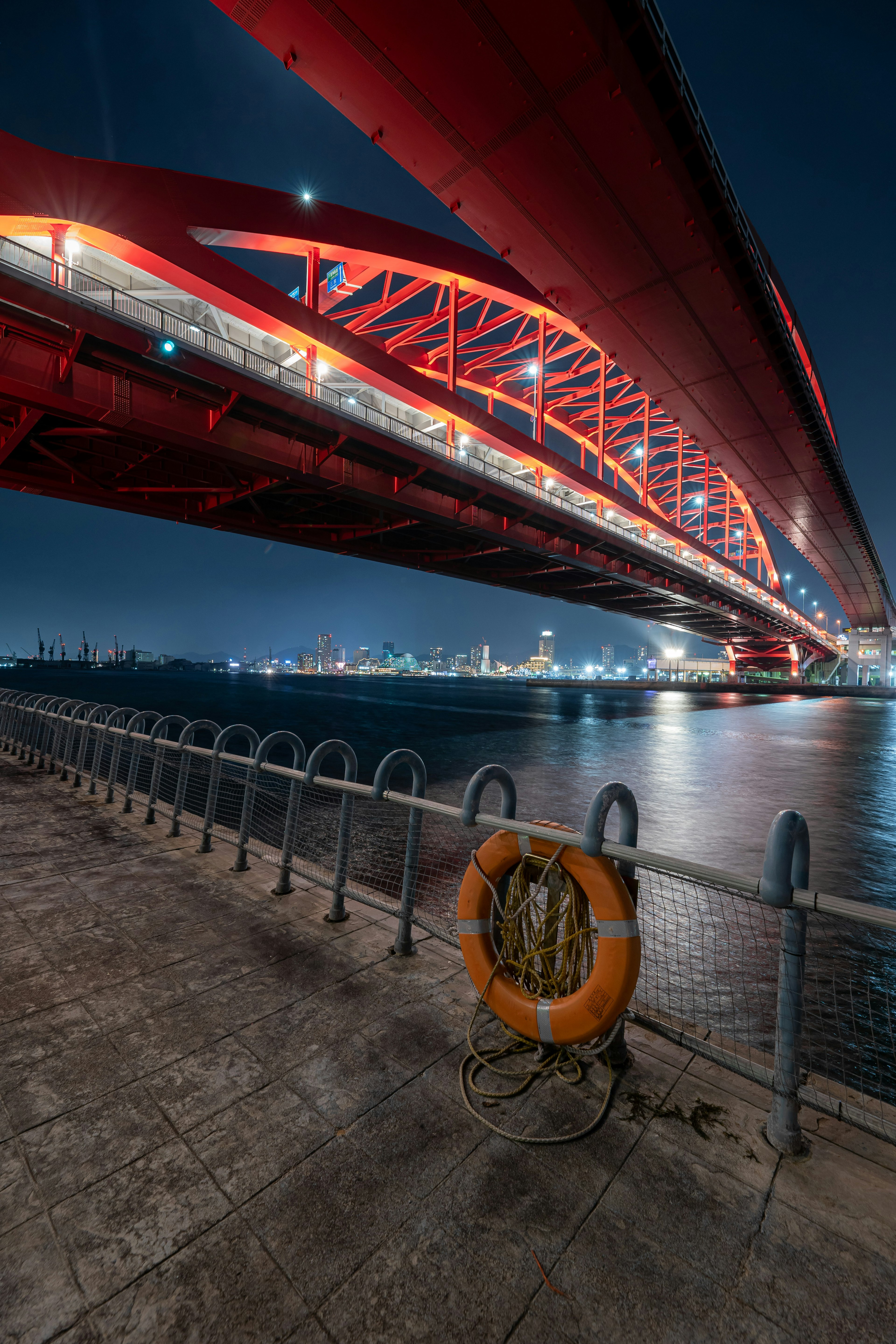 夜间照亮的红色桥梁和前景的救生圈