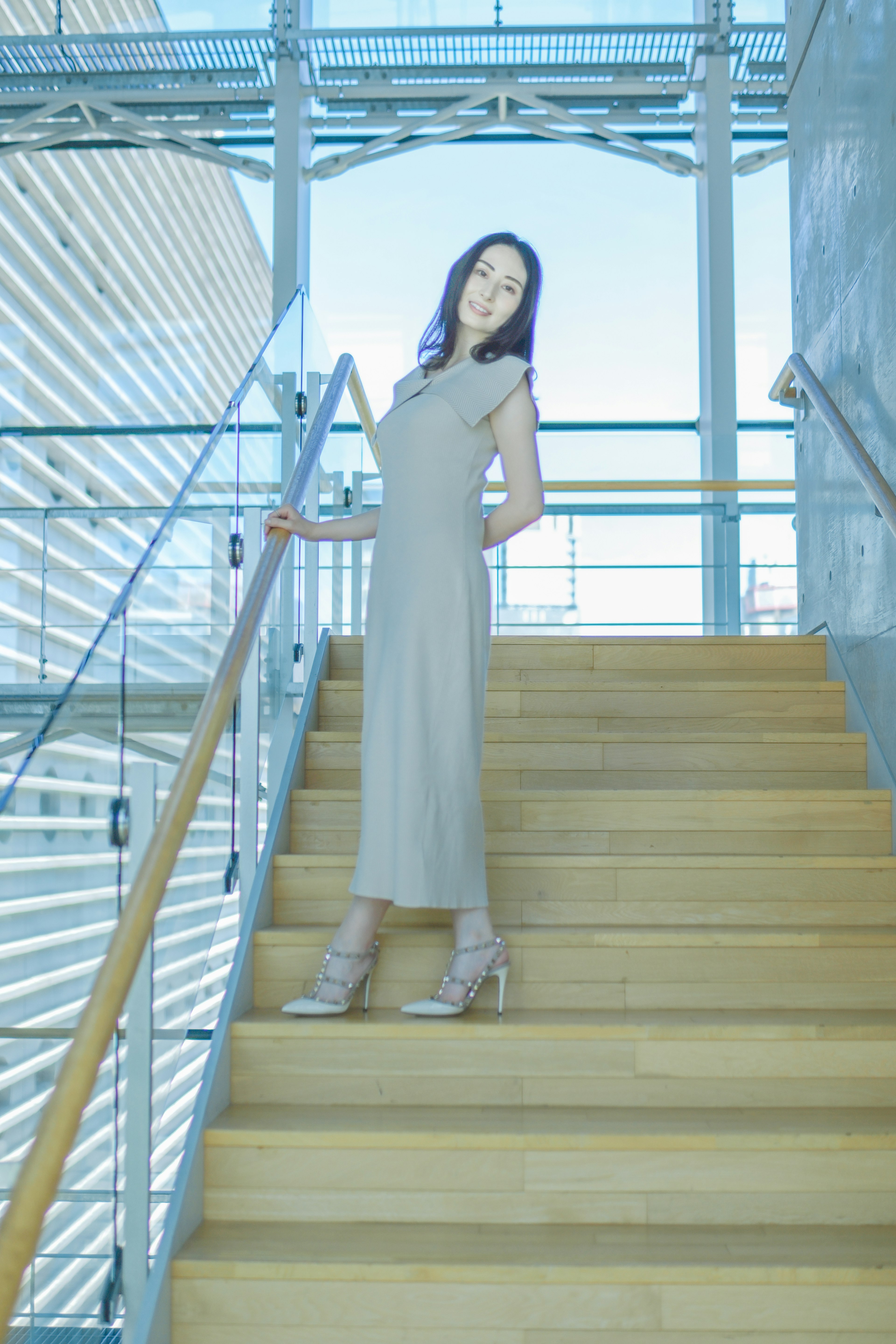 A female model standing on stairs wearing a gray dress