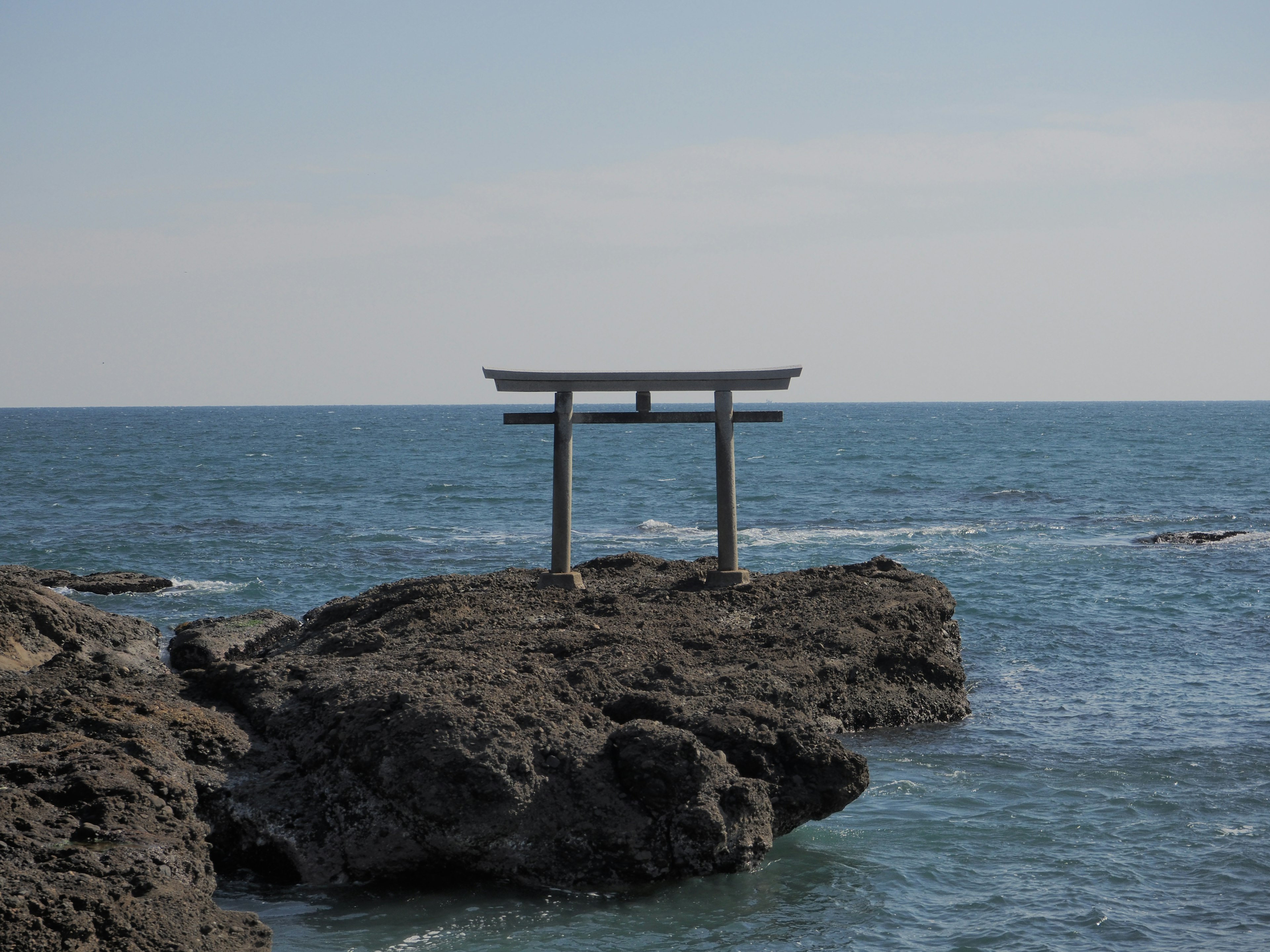 Puerta torii en una costa rocosa cerca del océano