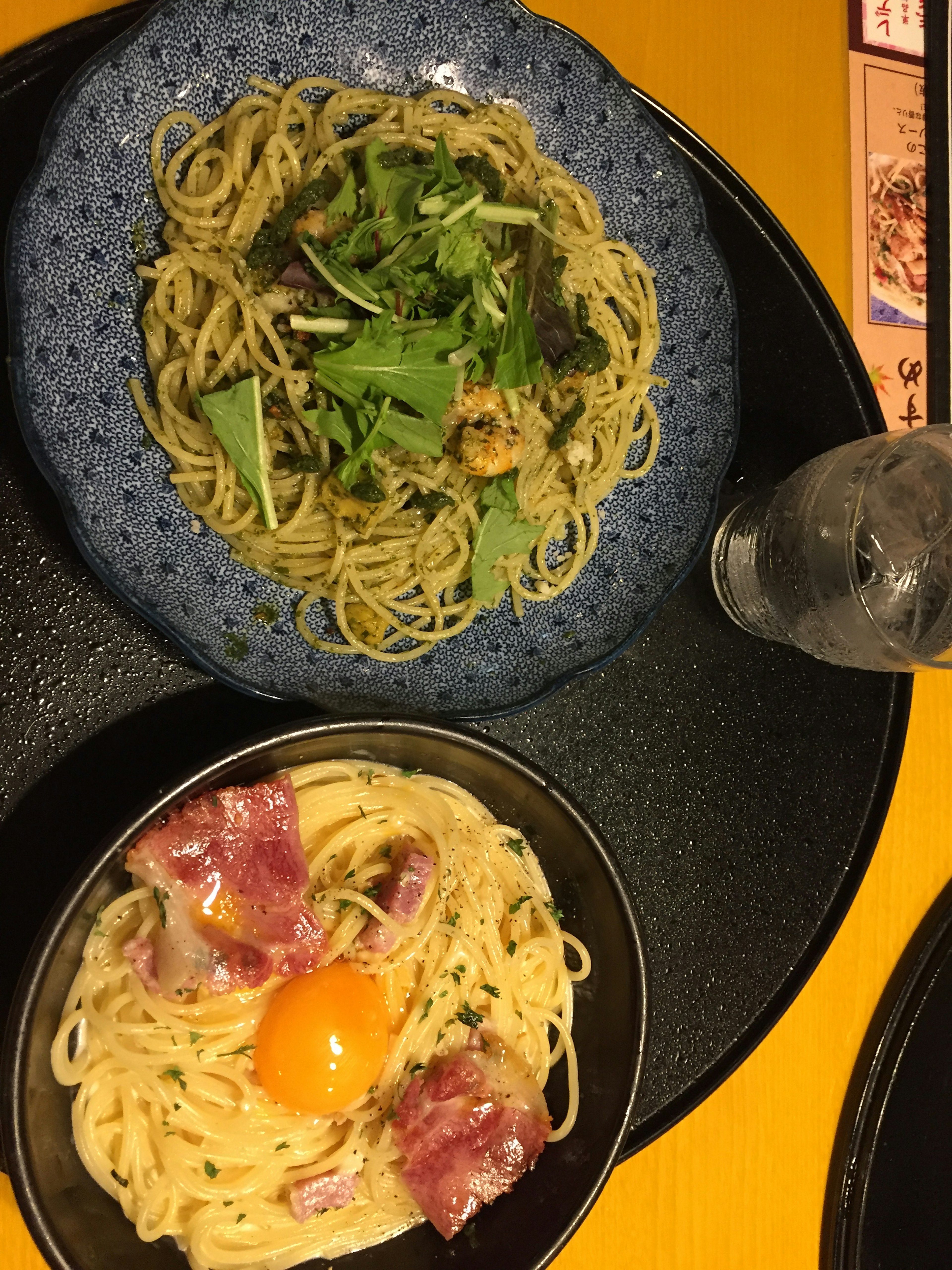 Ein Teller mit grüner Gemüse-Pasta und eine Schüssel mit cremiger Pasta mit Ei und Speck