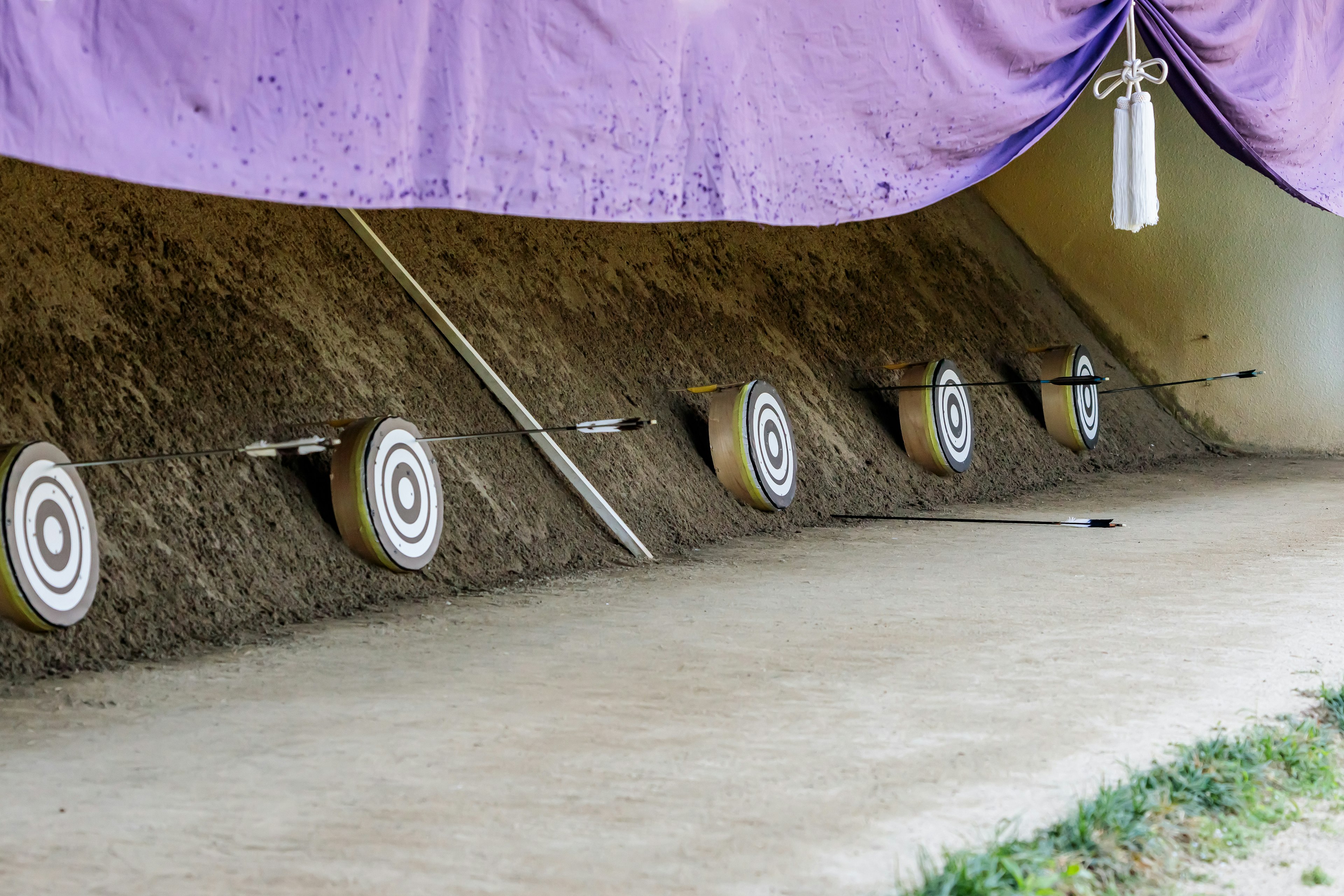 Archery range with targets lined up against a dirt backdrop and purple drapery