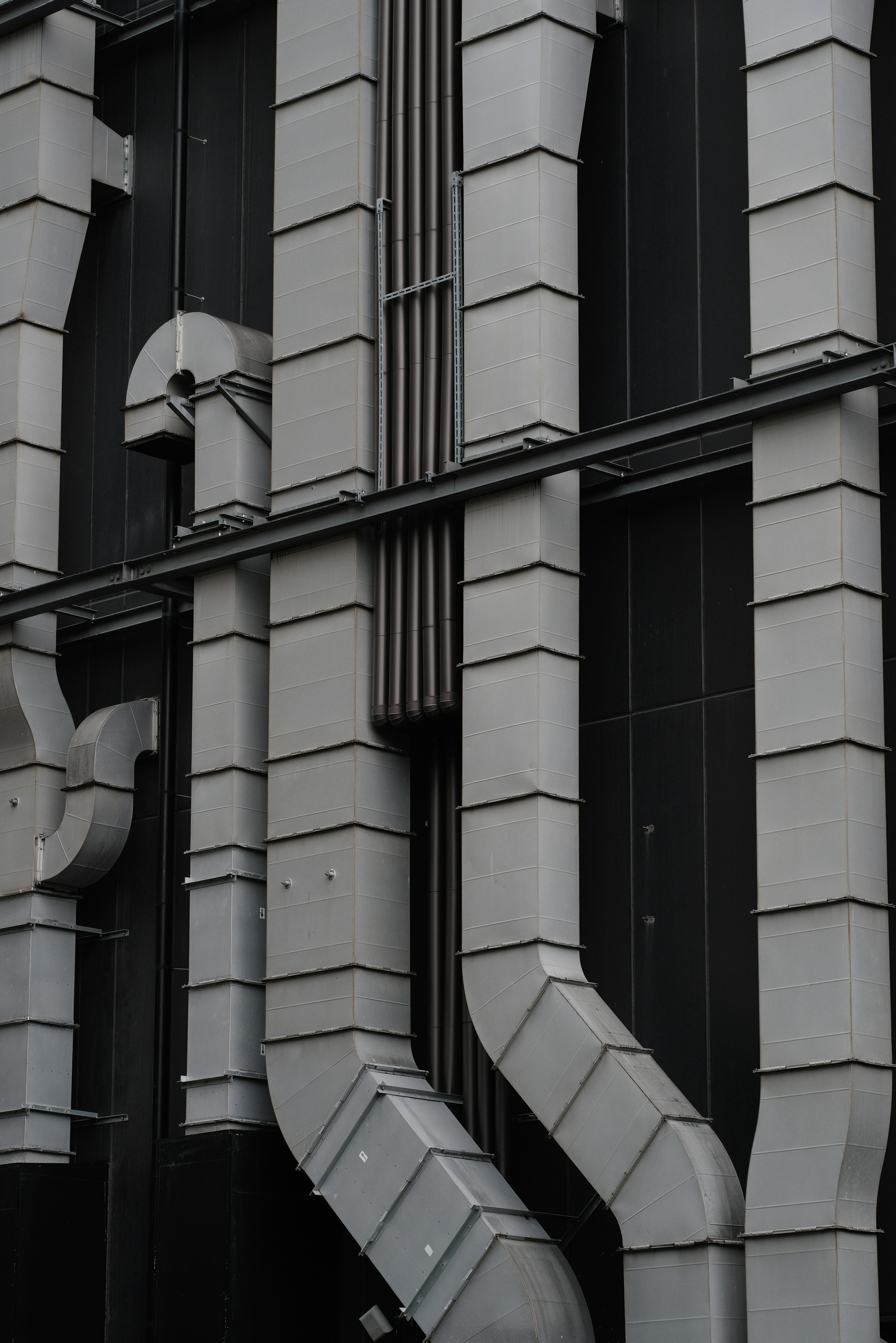 Detailed view of metal pipes and ducts attached to a building's exterior wall