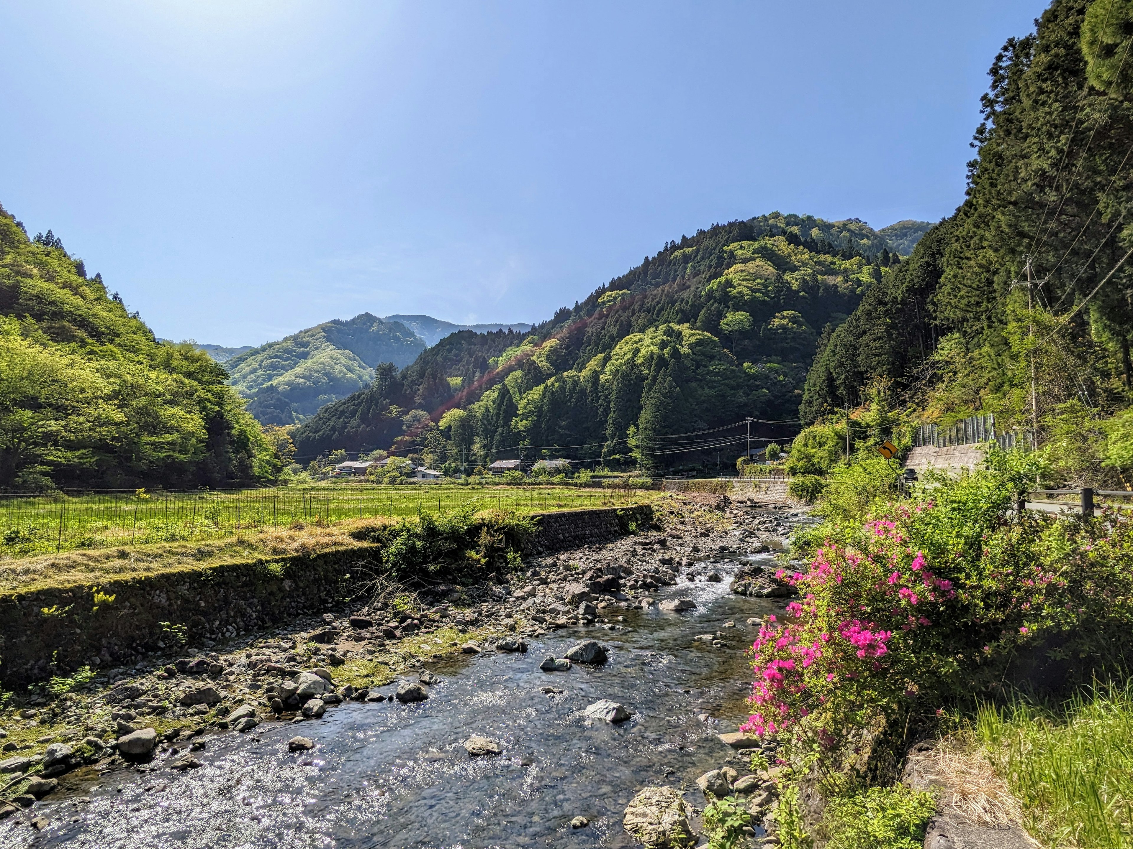 Vista escénica de montañas y un río bajo un cielo azul claro Montañas verdes y un banco de río rocoso