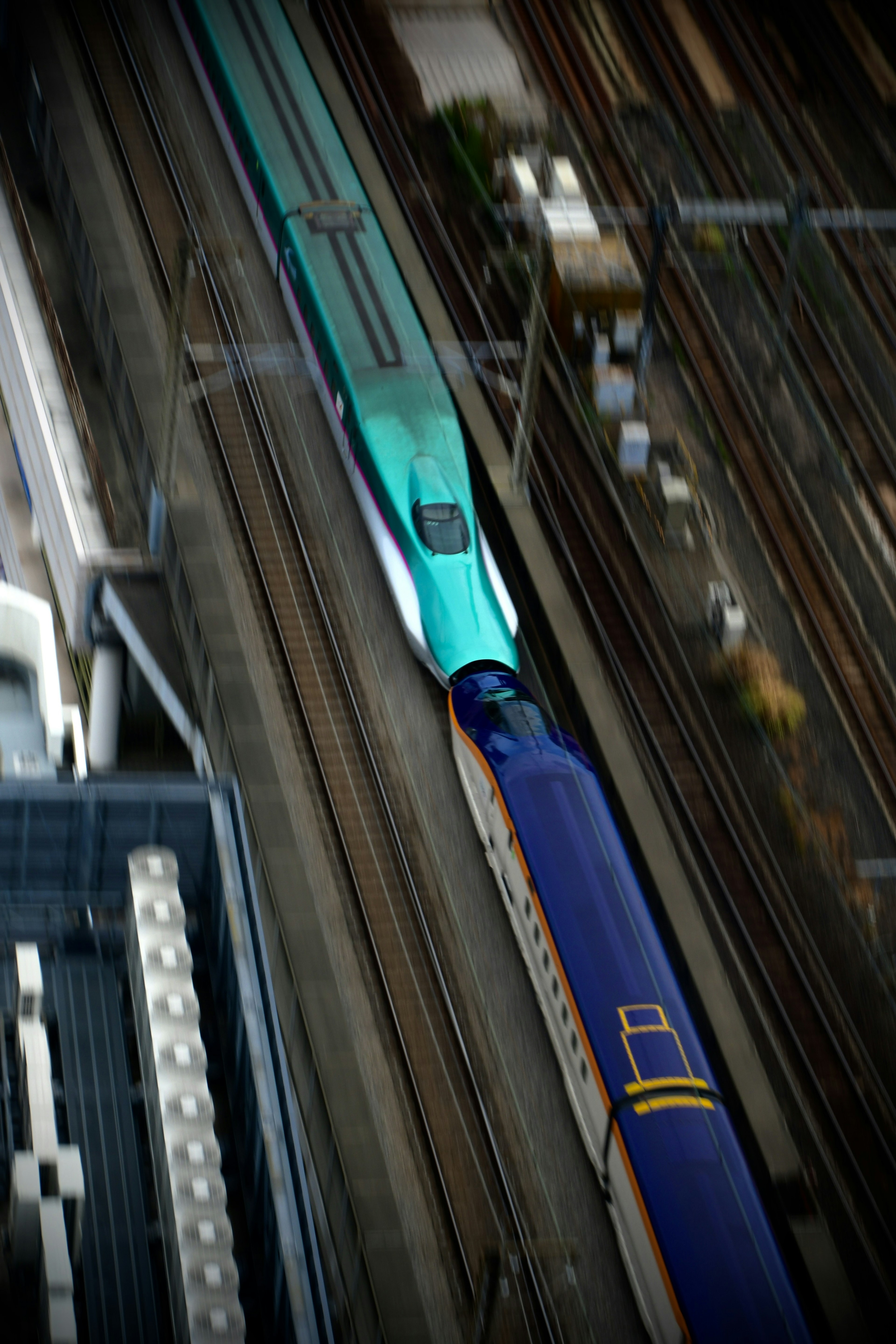 High-speed train in green and blue crossing tracks