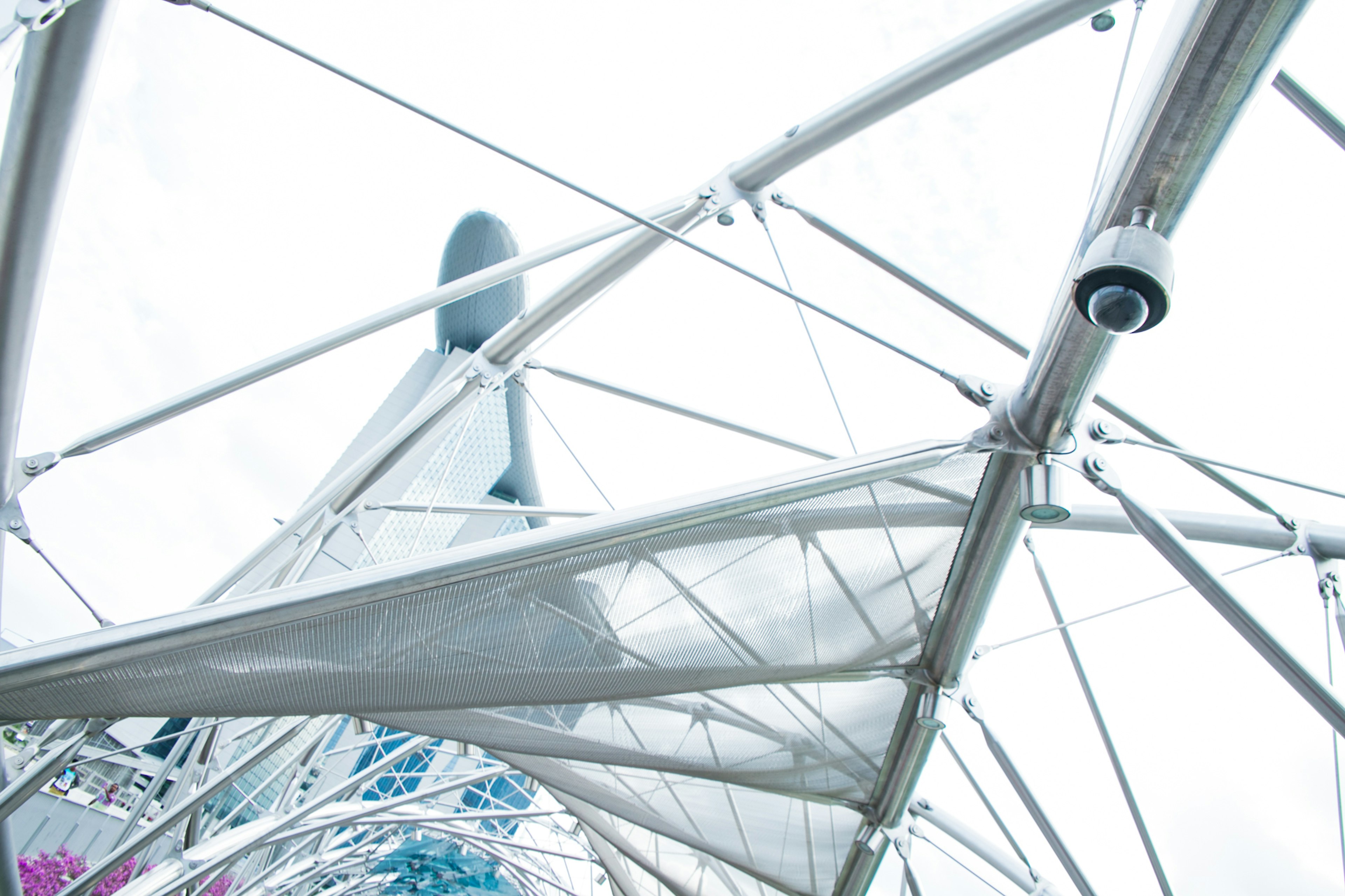 Photo looking up at a structure under a transparent roof featuring steel frame and mesh elements