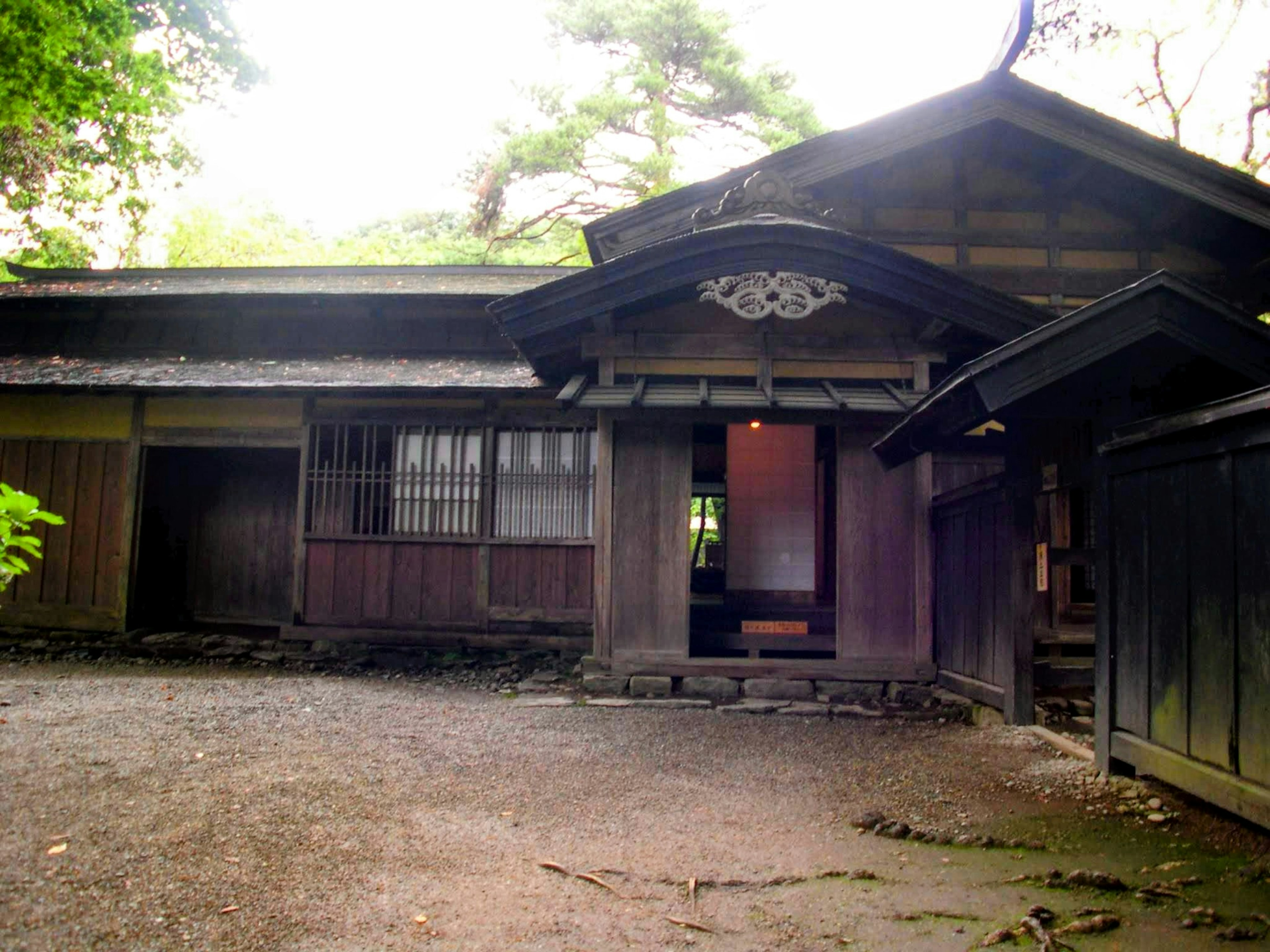 Außenansicht eines traditionellen japanischen Holzhauses umgeben von üppigem Grün