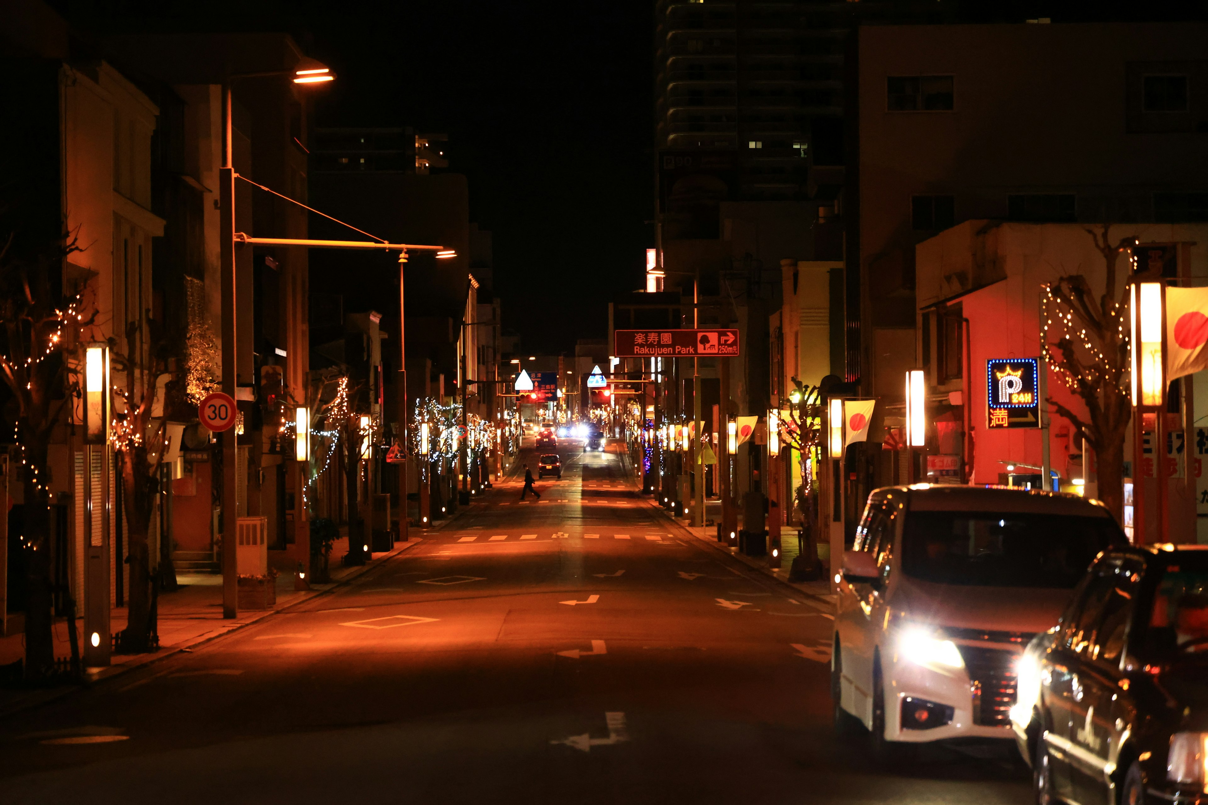 A street at night lined with lights and parked cars