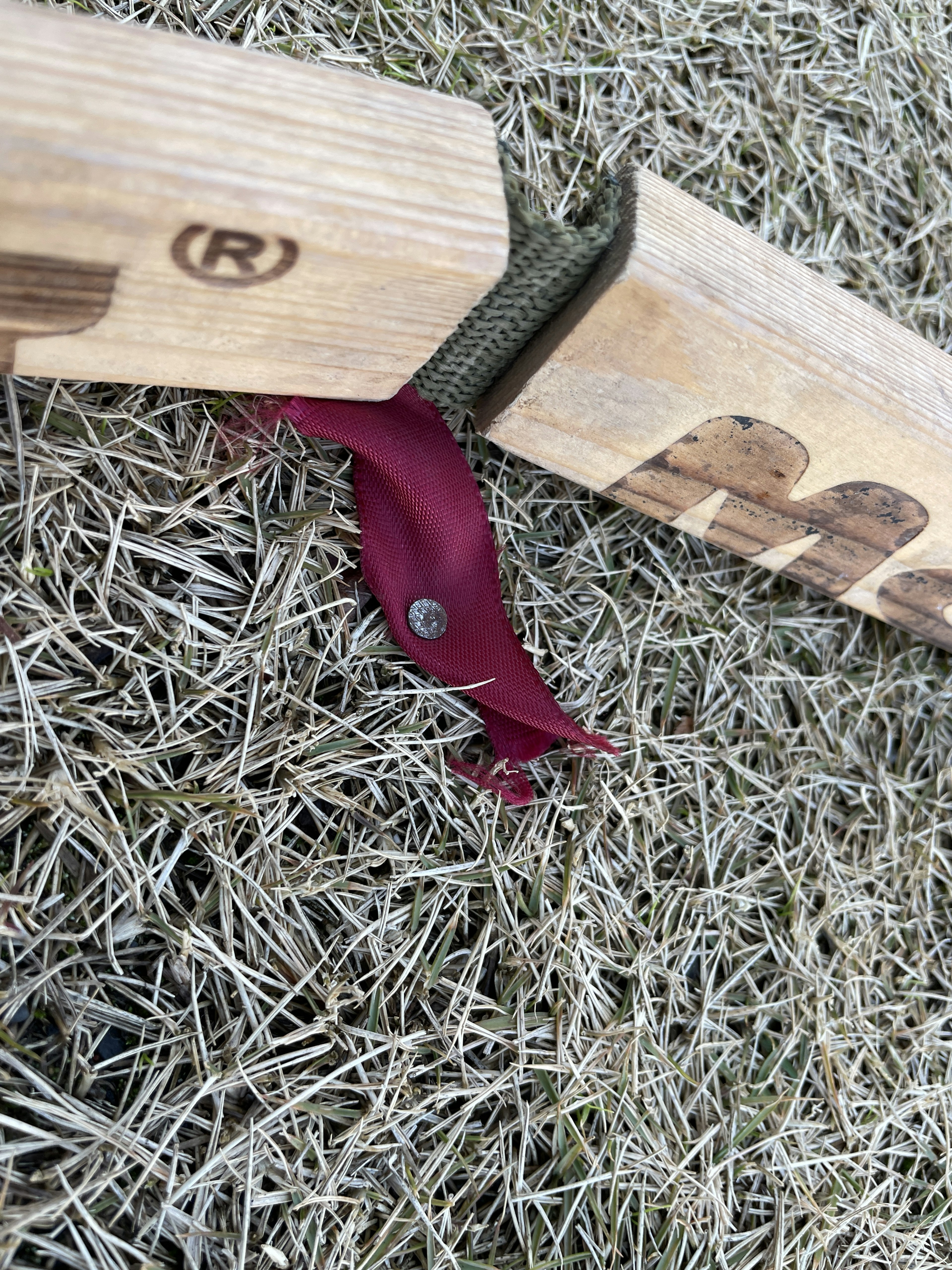 Holzmaßstab mit rotem Stoffetikett auf Gras liegend