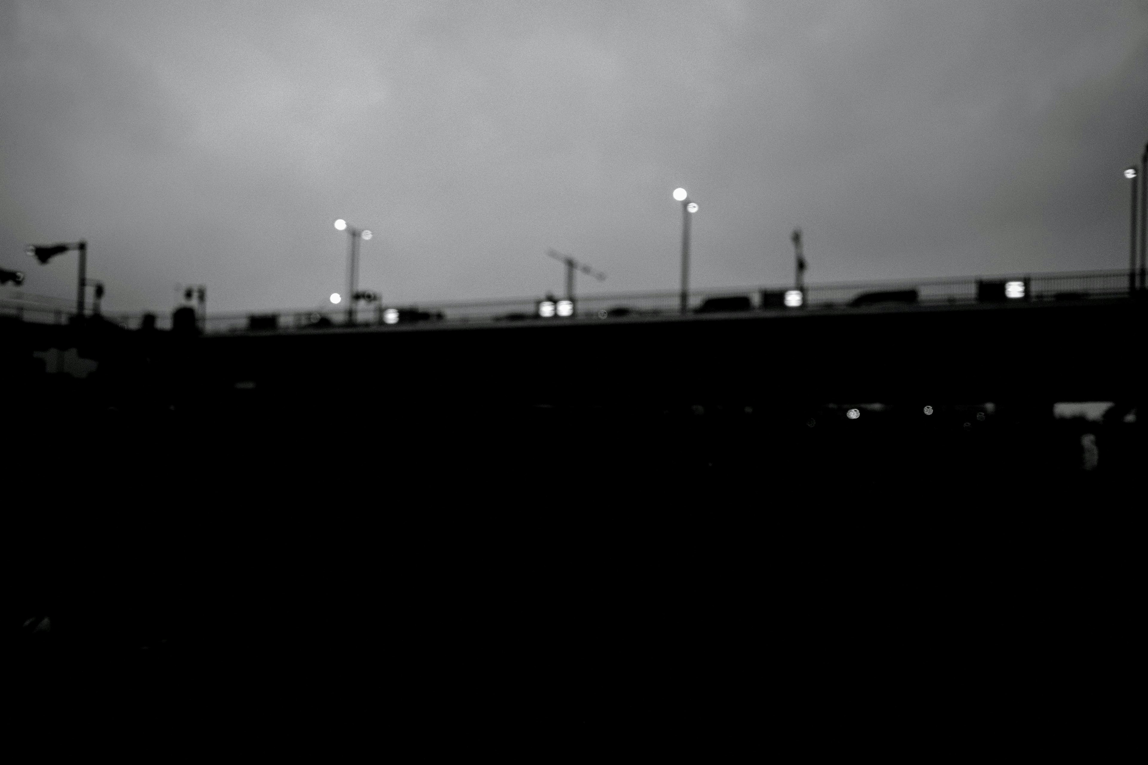 Silhouette d'un pont avec des lampadaires contre un ciel sombre