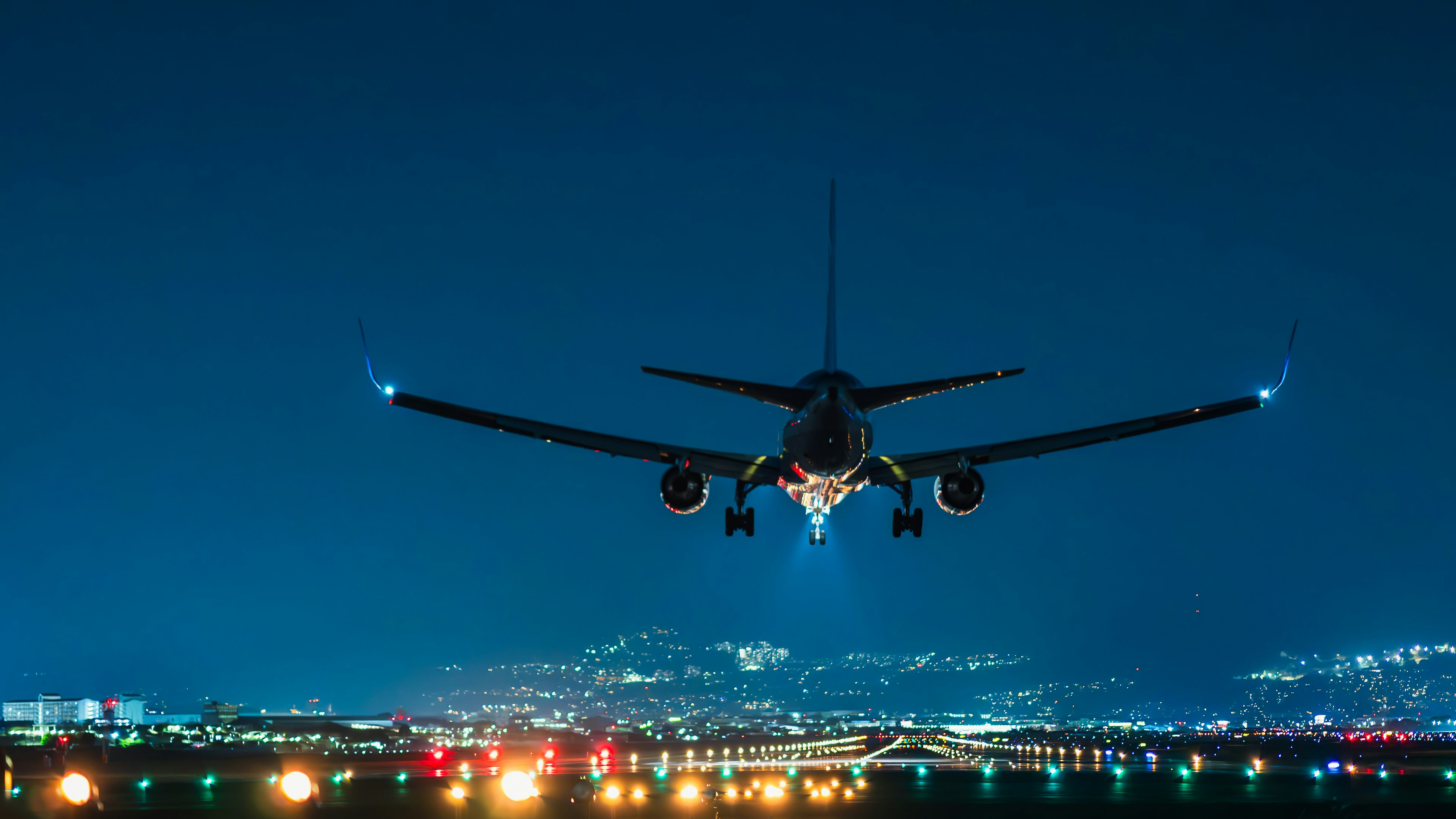 Airplane approaching at night over an airport runway