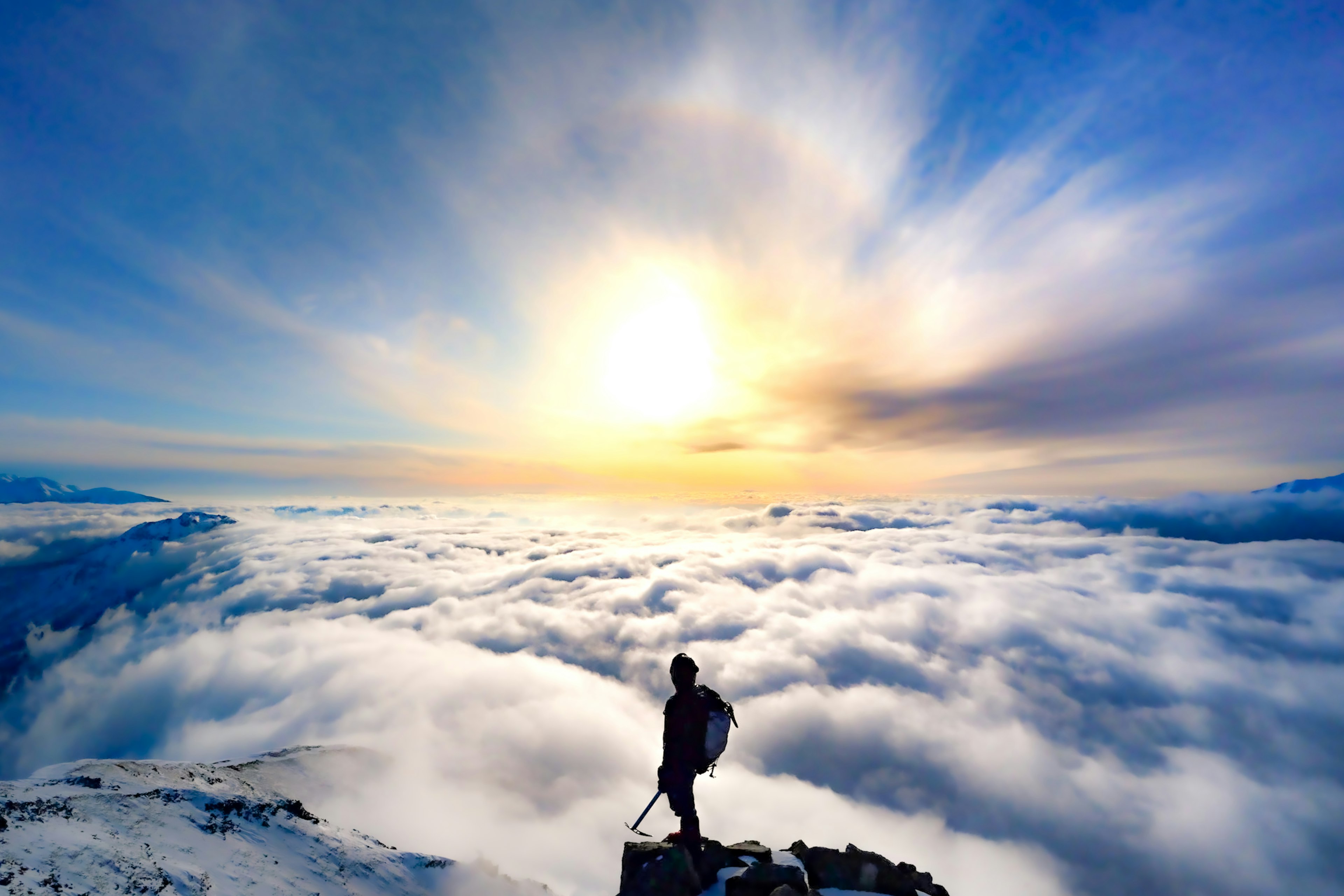 Hiker standing above a sea of clouds with a beautiful sunrise