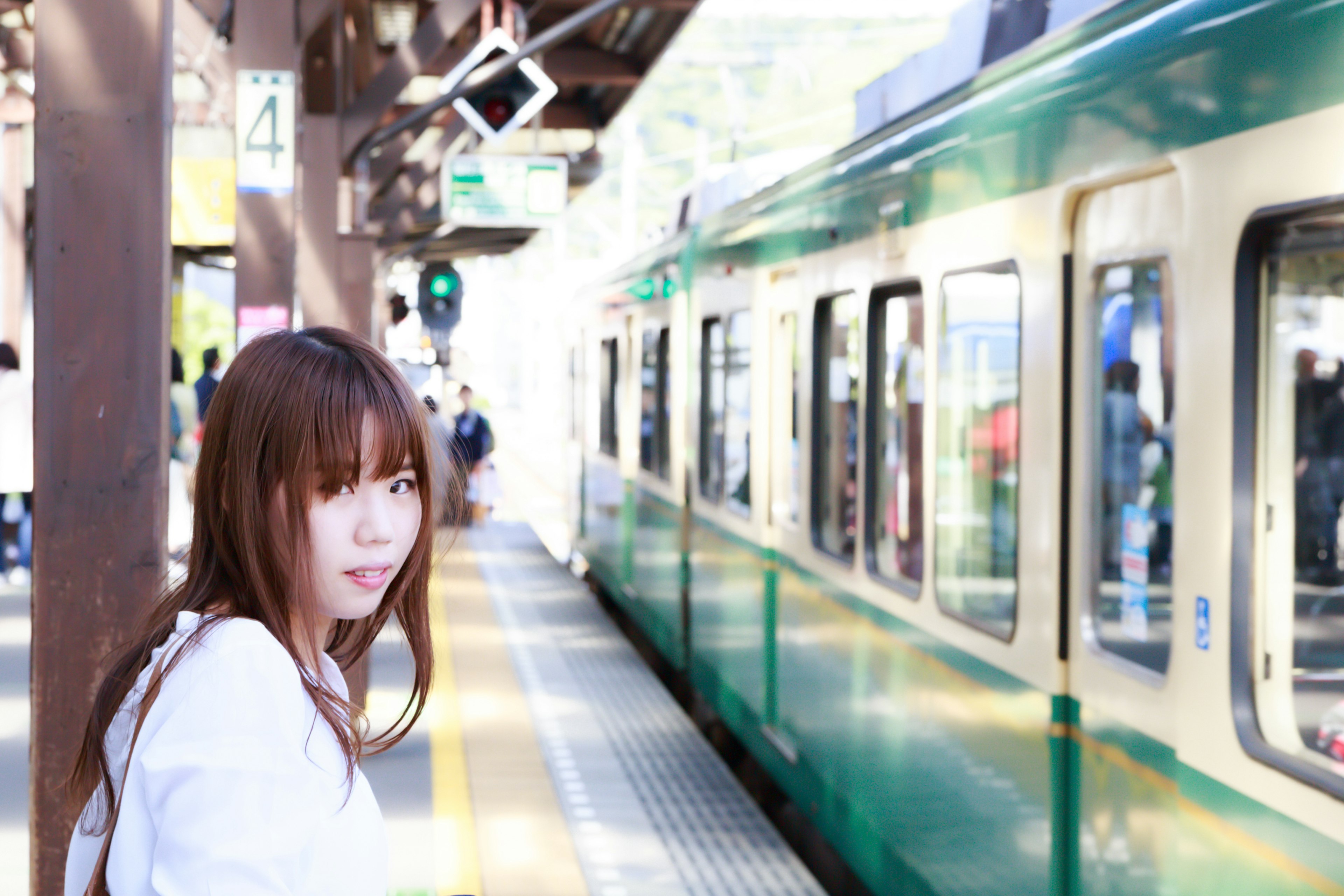 Woman standing at a train platform next to a green train