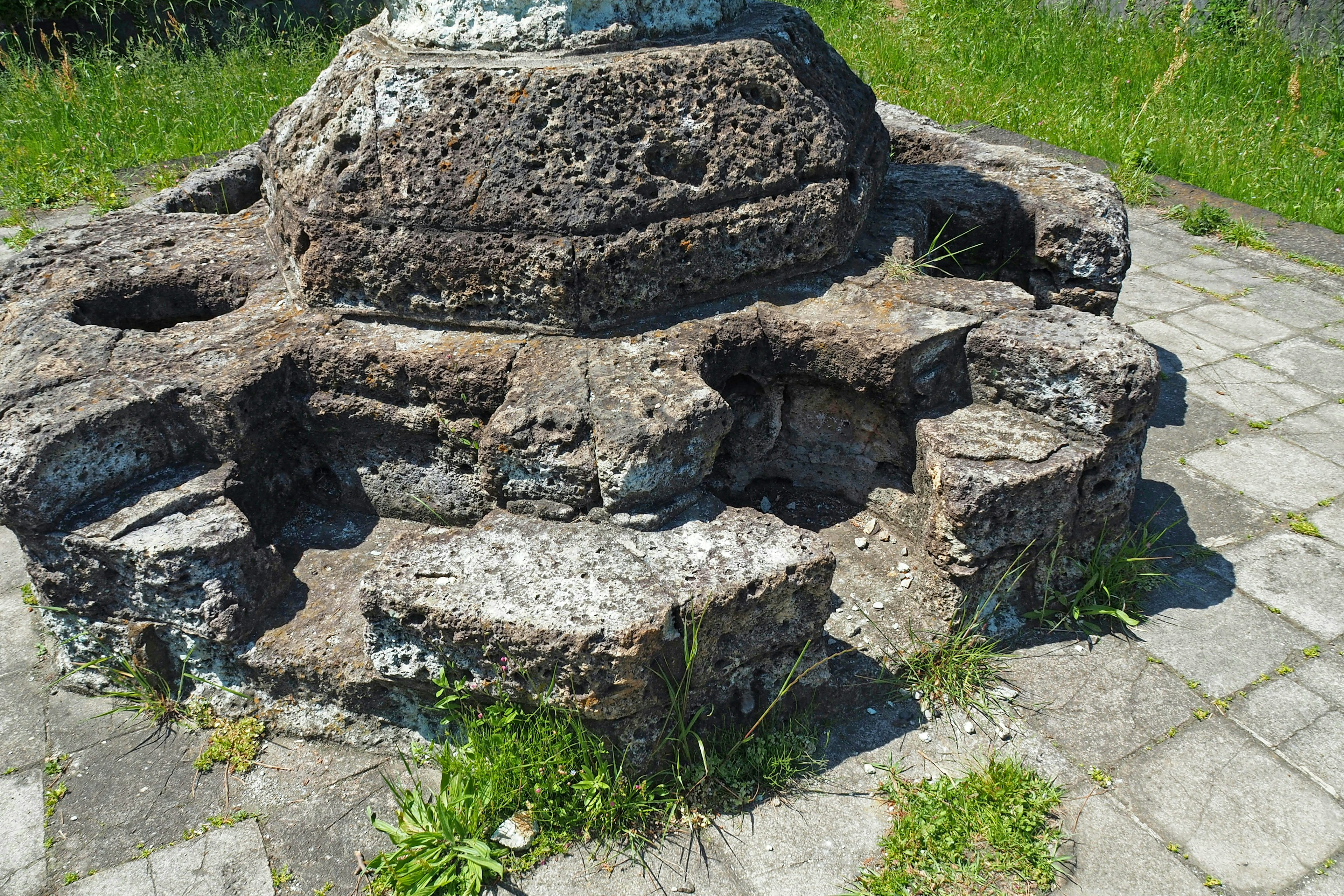 Stone base with overgrown grass and surrounding landscape