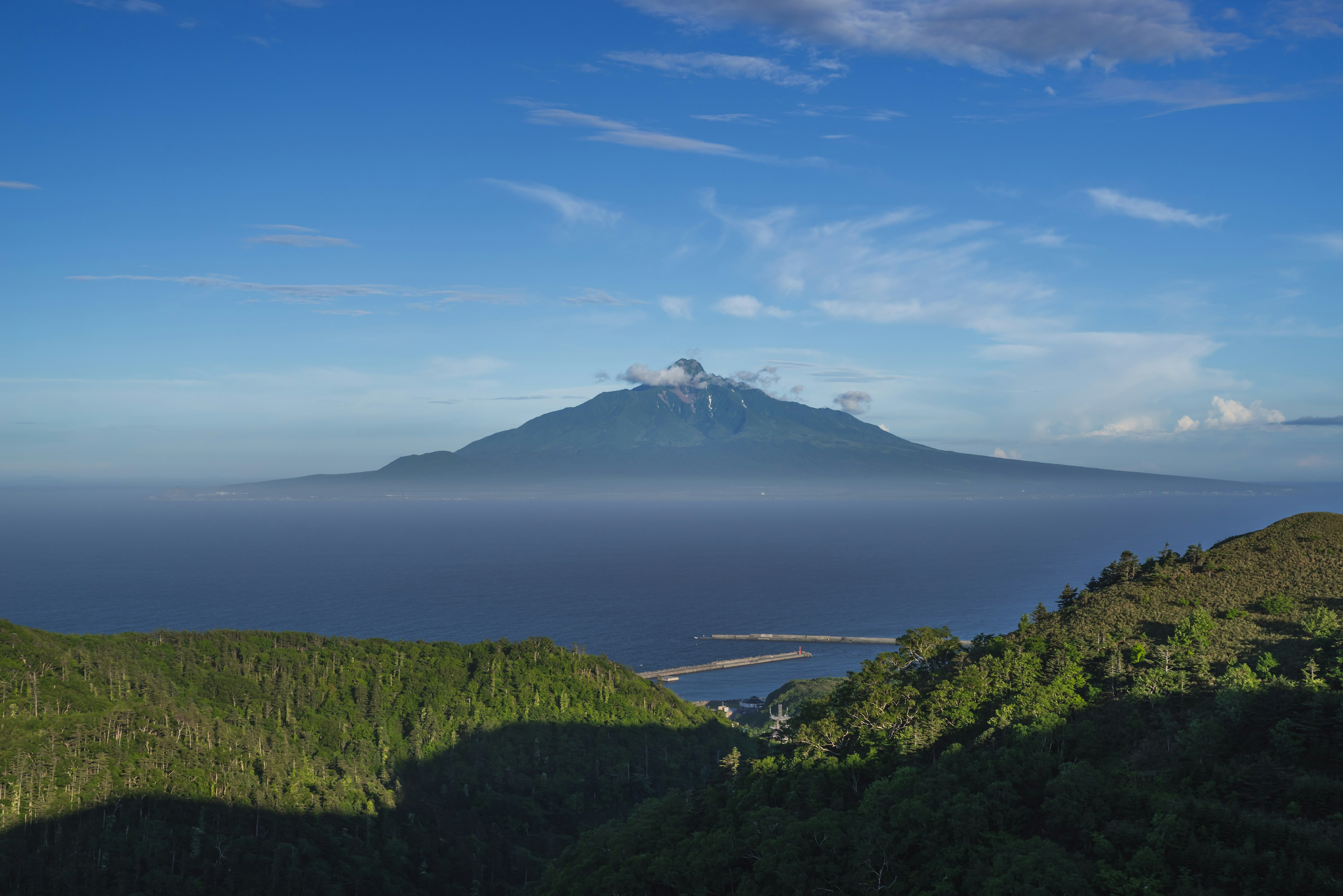 Vue panoramique d'un volcan entouré de ciel bleu et de nuages montagnes verdoyantes et océan