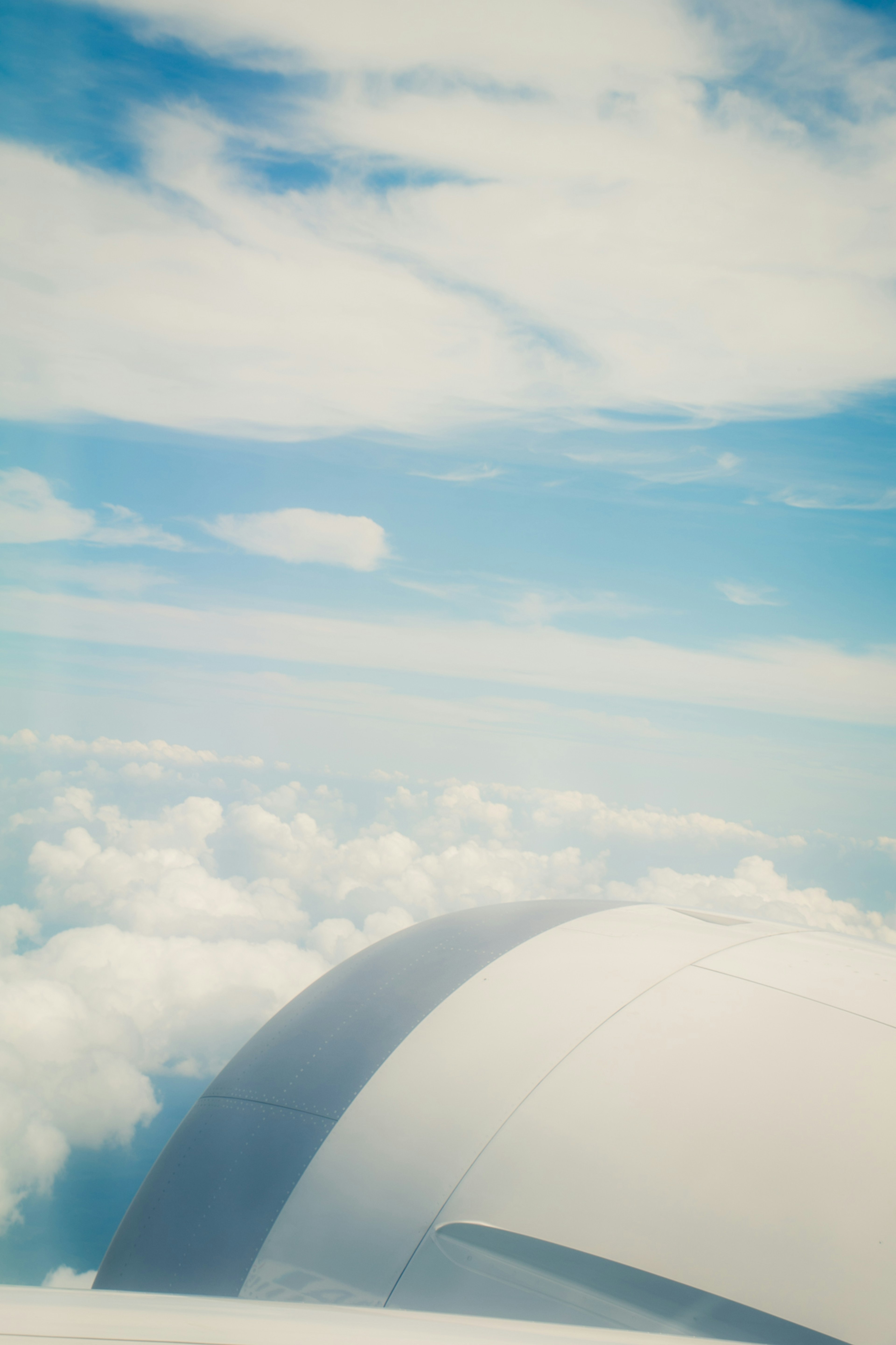 Airplane wing above clouds under a blue sky