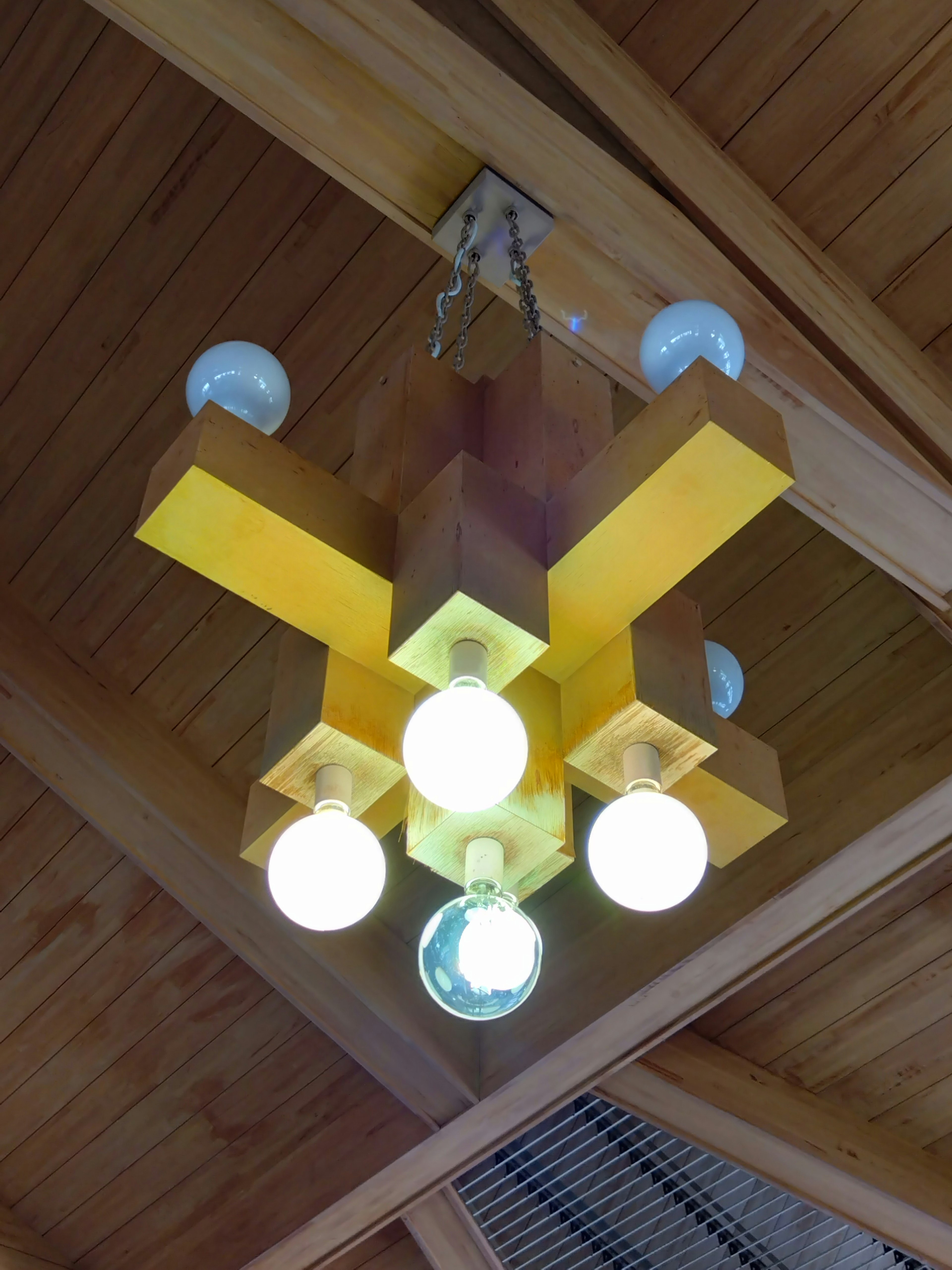 Chandelier en bois jaune avec des ampoules blanches dans un design unique