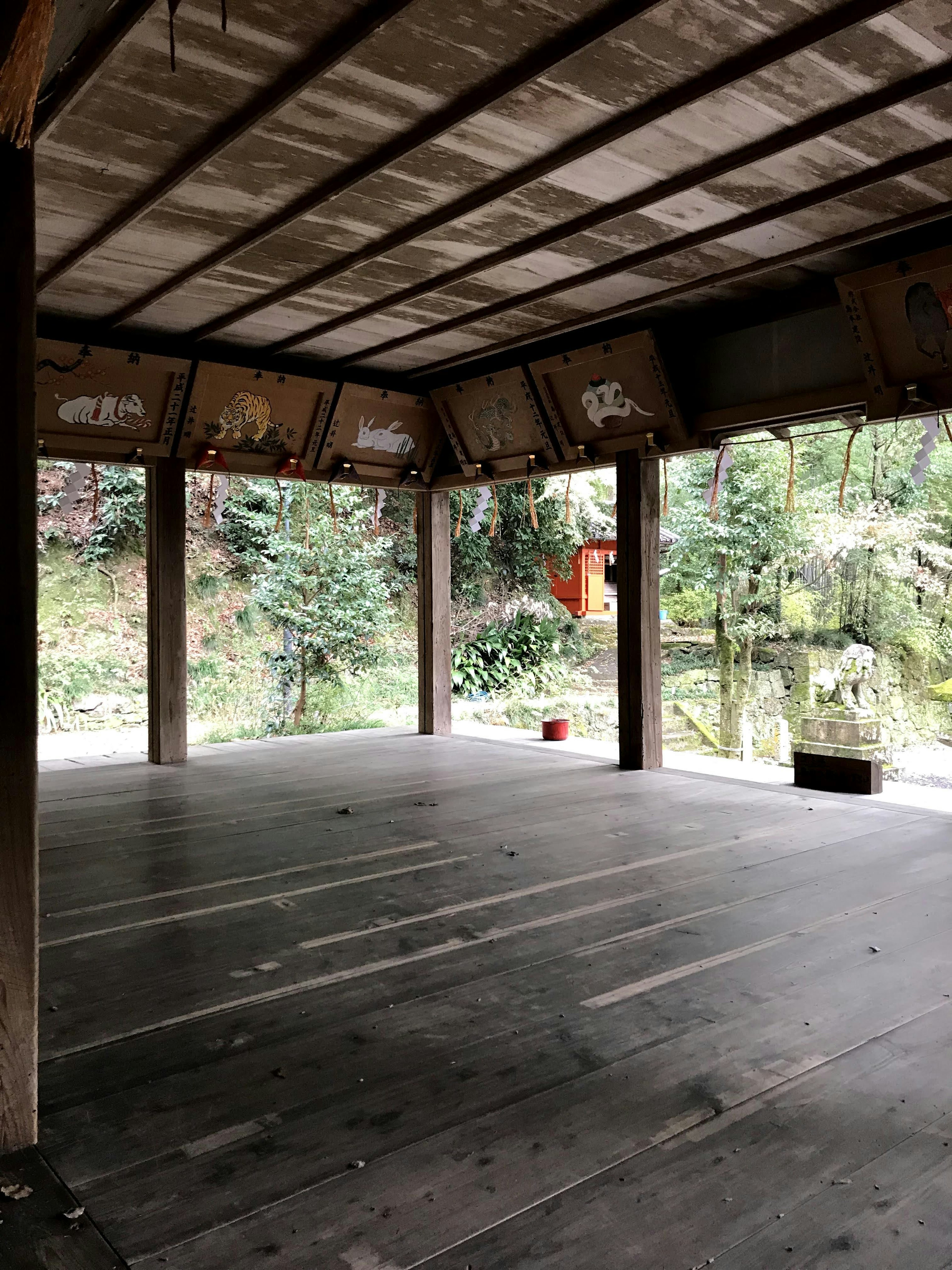 Spacious room with wooden floor and pillars featuring green landscape visible through windows