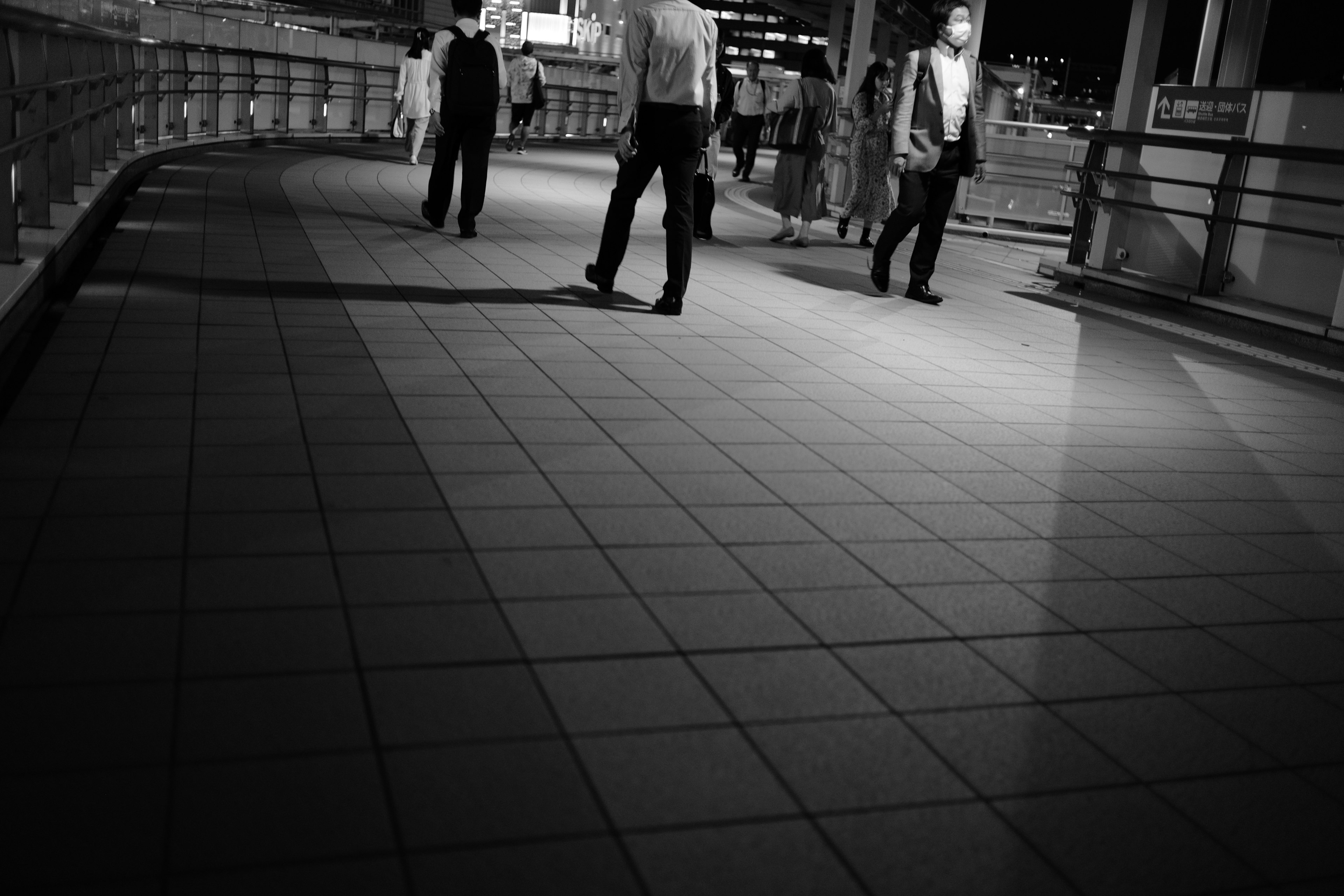 Silhouetten von Menschen, die nachts in einer Stadt in Schwarzweiß gehen