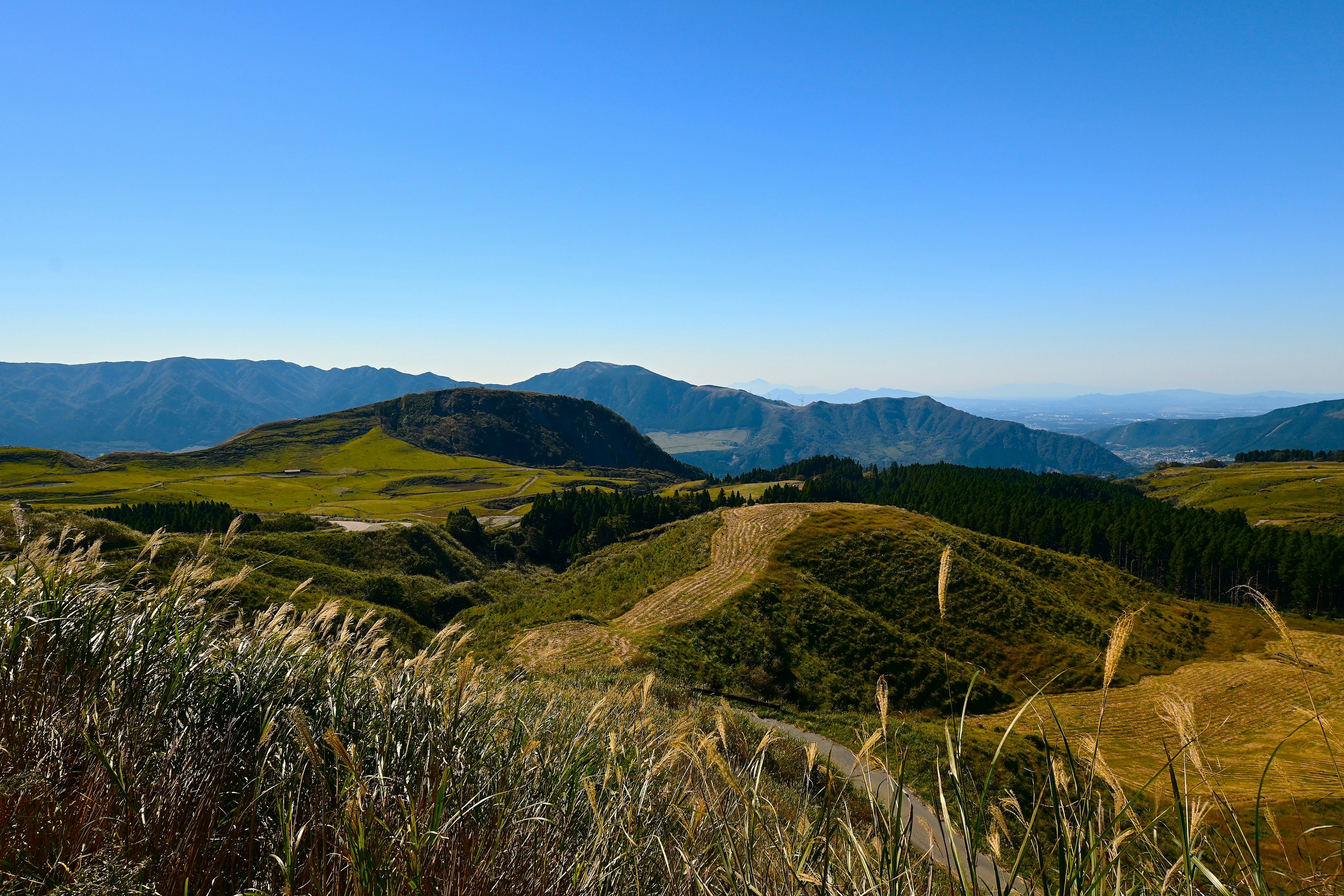 Paisaje de colinas verdes y montañas distantes bajo un cielo azul claro