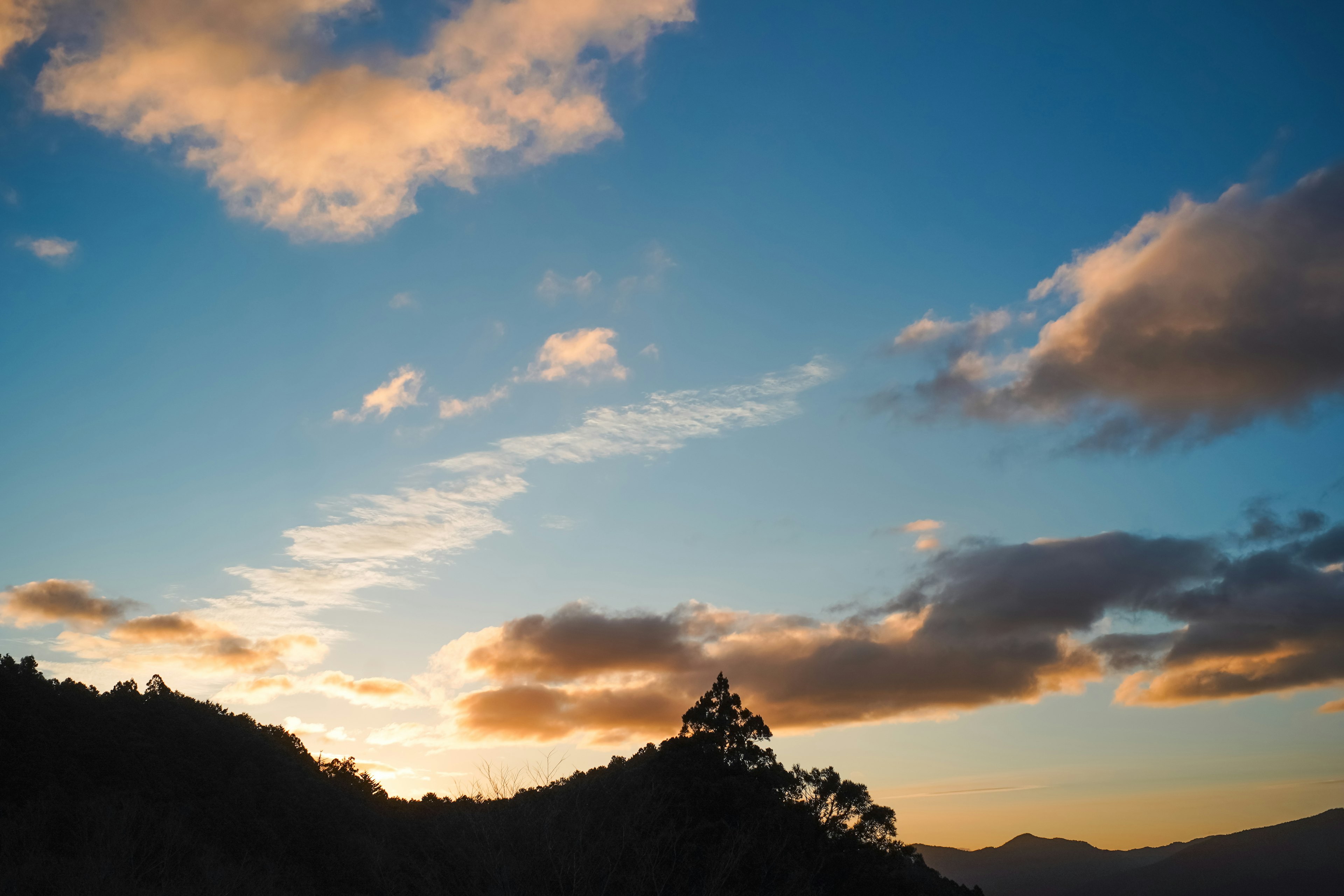 美しい夕焼けの空に浮かぶ雲と山のシルエット