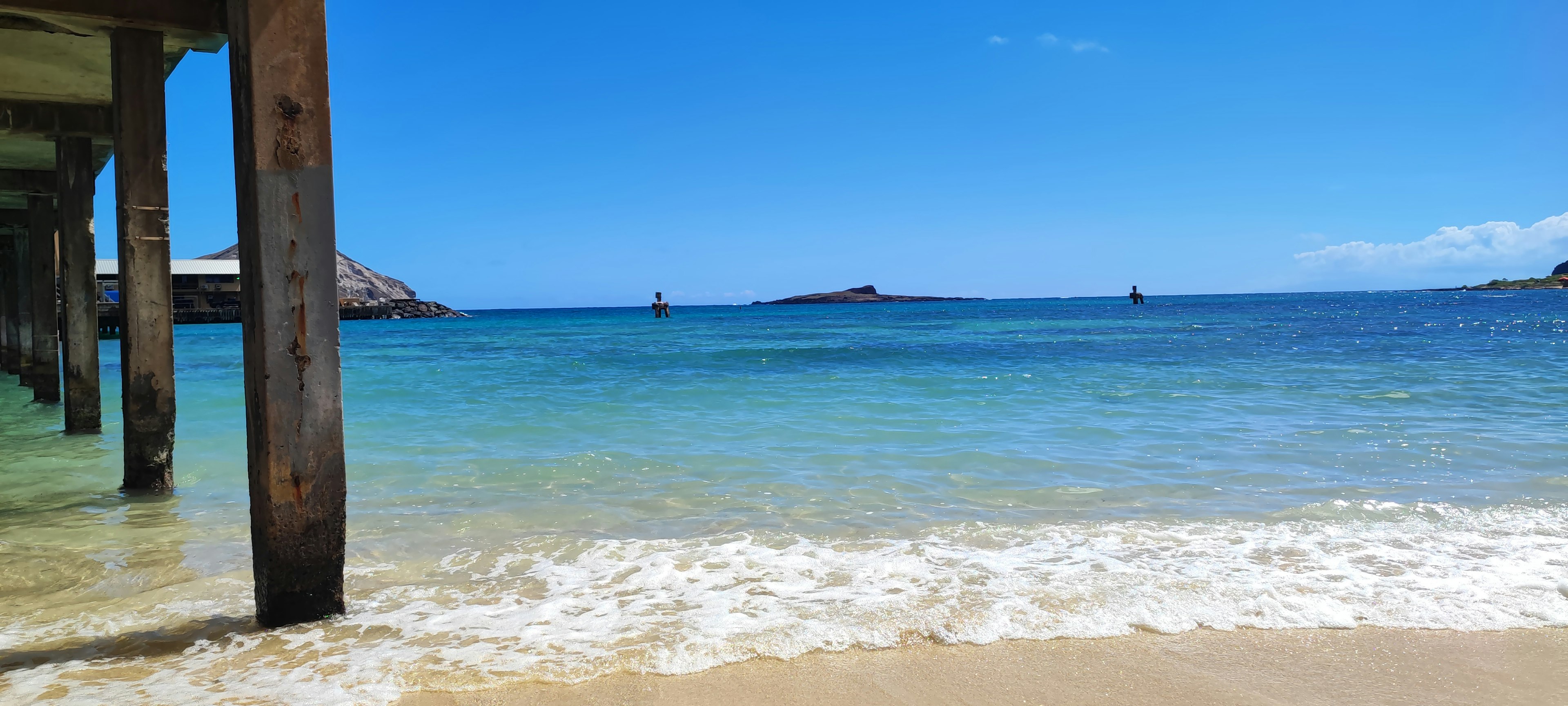 Vue pittoresque de l'océan bleu et de la plage de sable avec un quai et des îles au loin