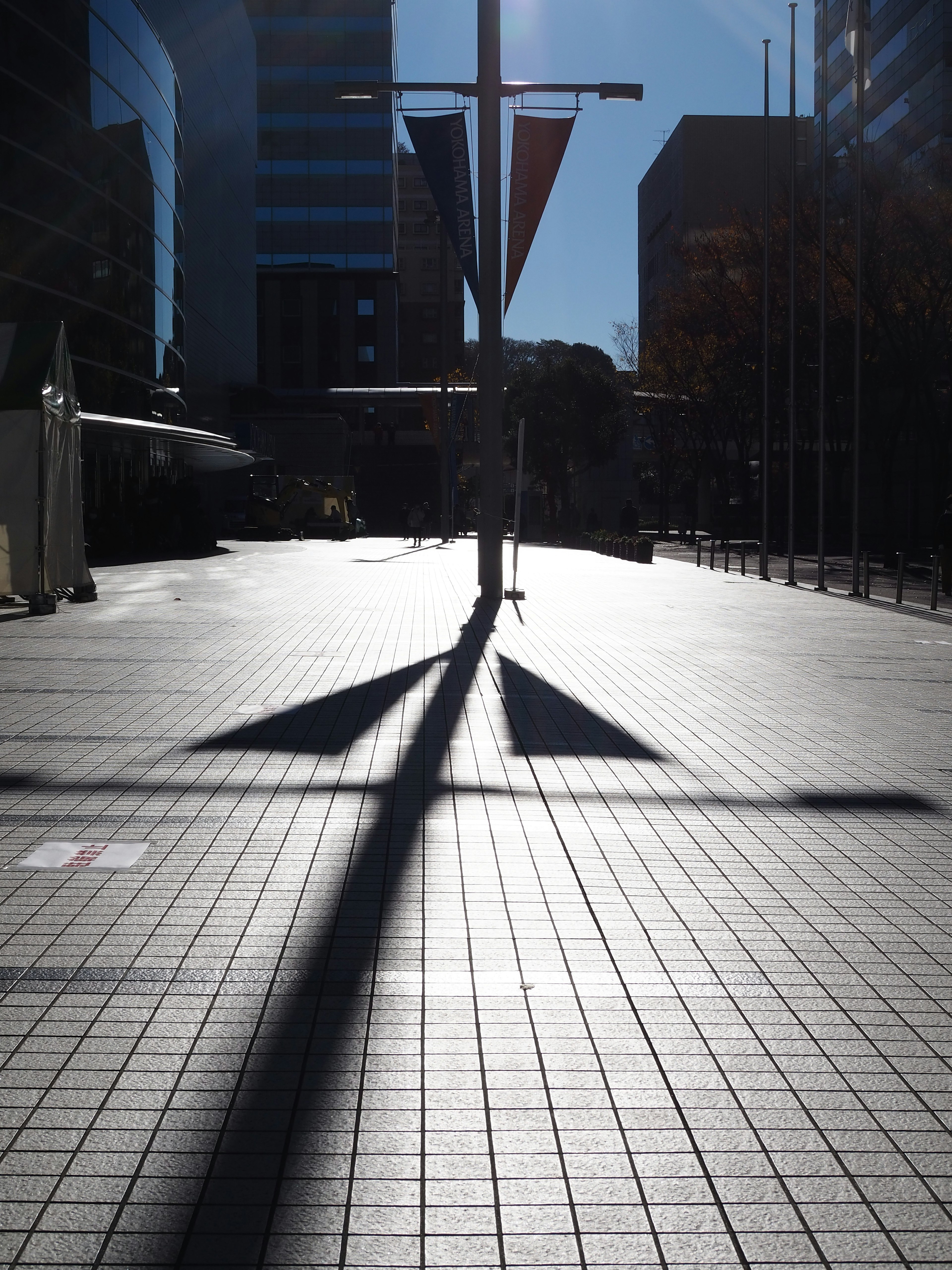 Plaza urbaine avec des ombres projetées par une croix et des bâtiments sous un soleil éclatant