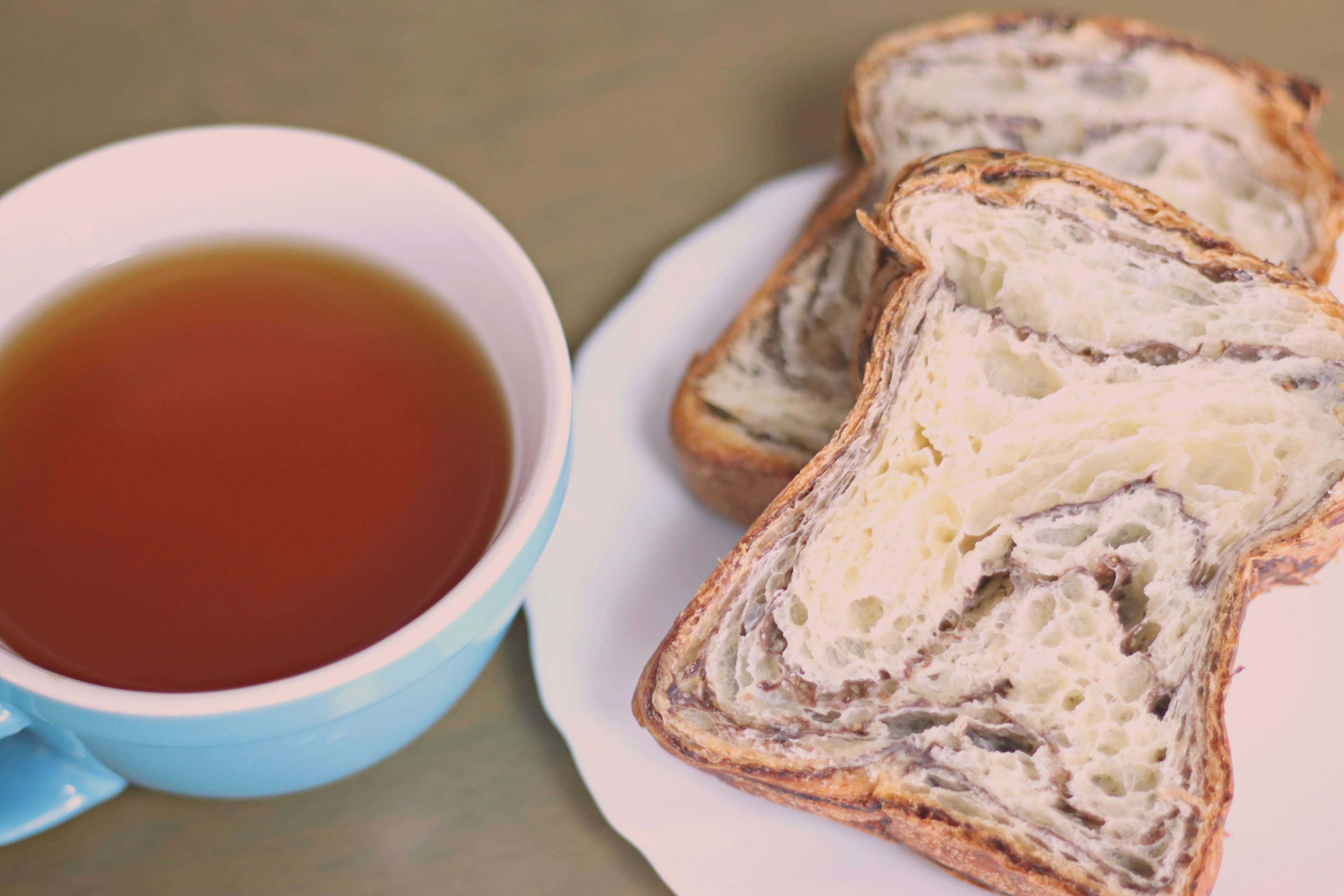 Eine blaue Tasse Tee neben Scheiben von Marmorbrot