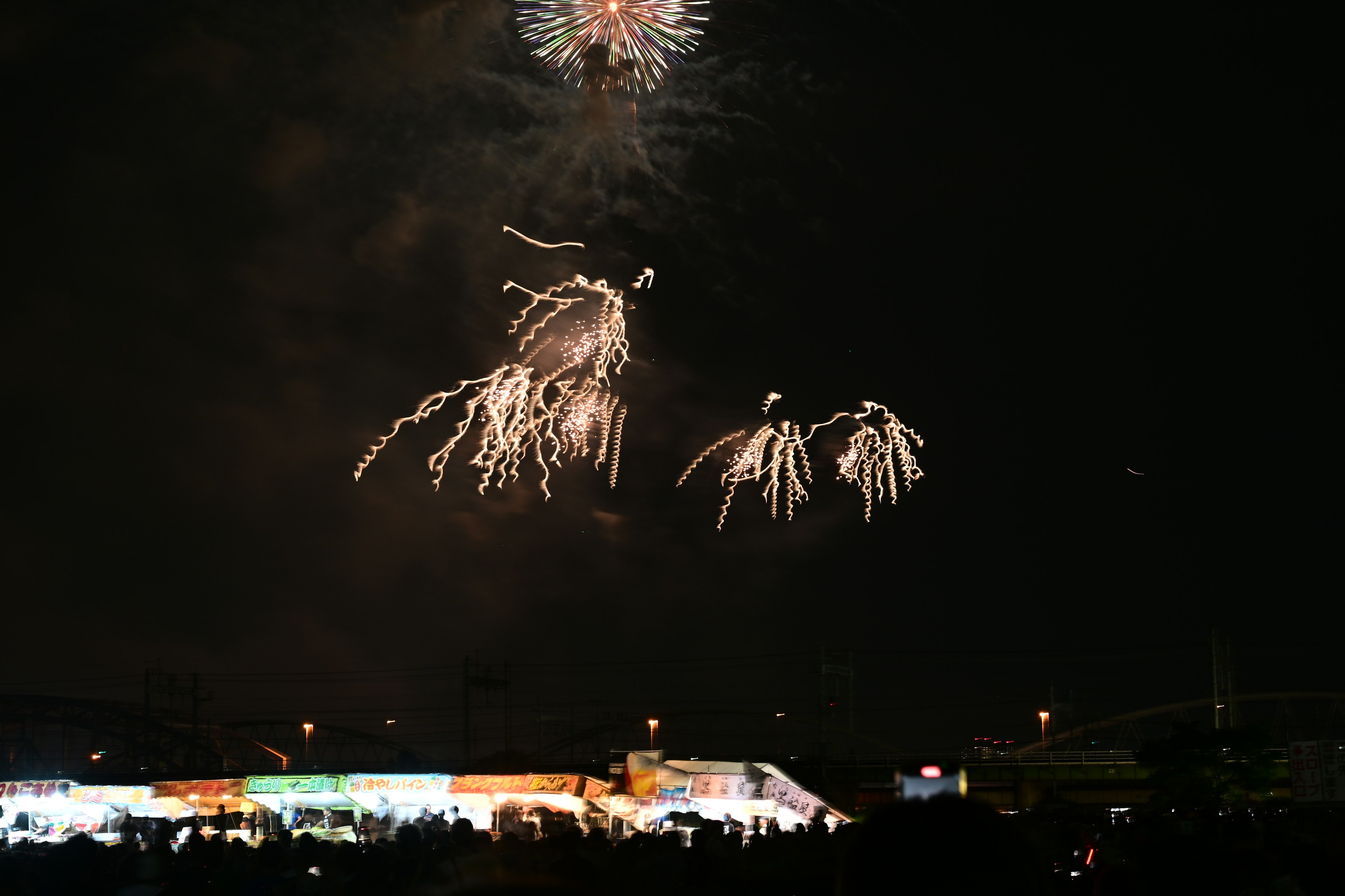 Spektakuläres Feuerwerk erhellt den Nachthimmel mit Silhouetten von Zuschauern