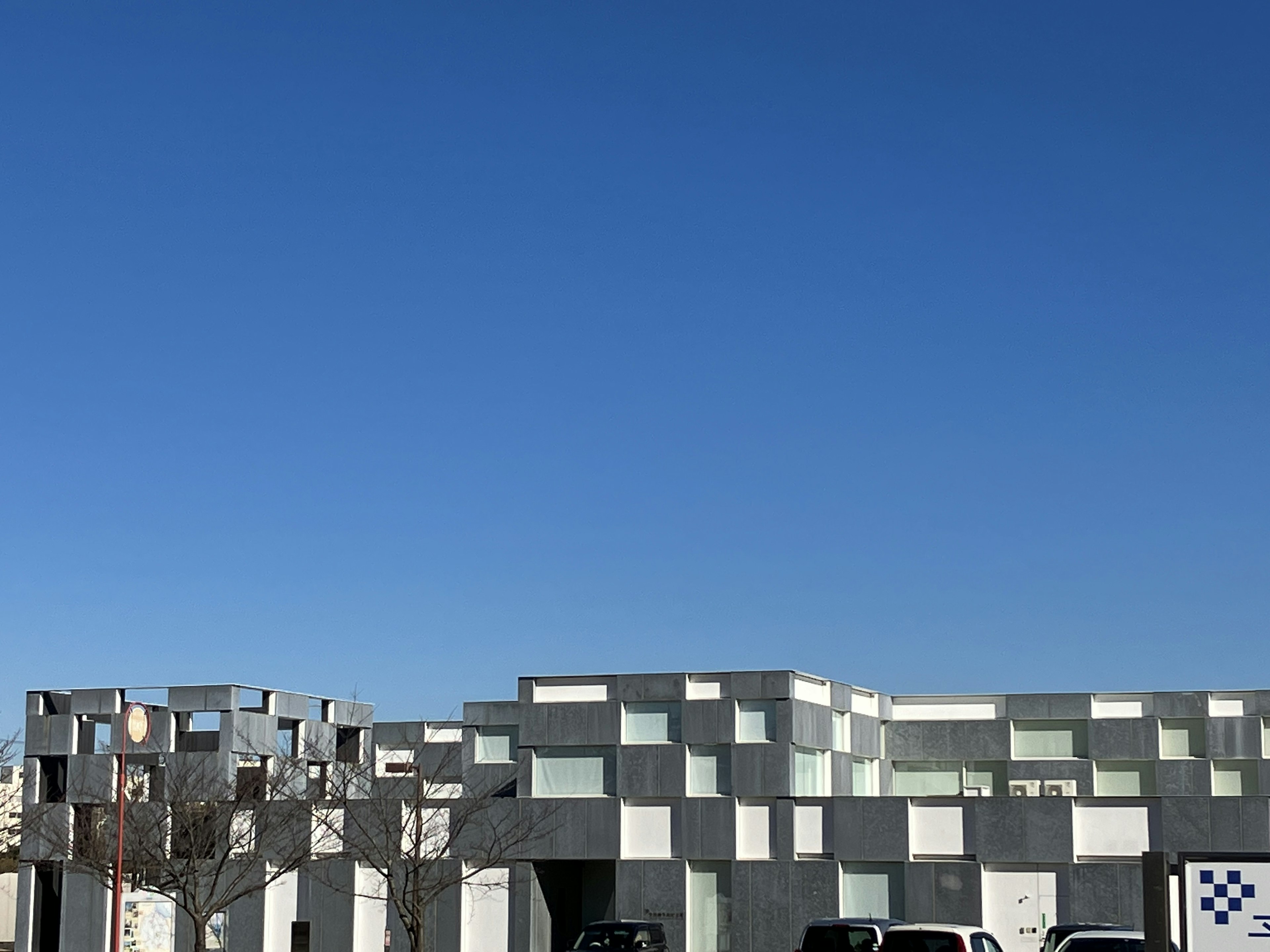 Unique modern building design under a clear blue sky featuring numerous windows