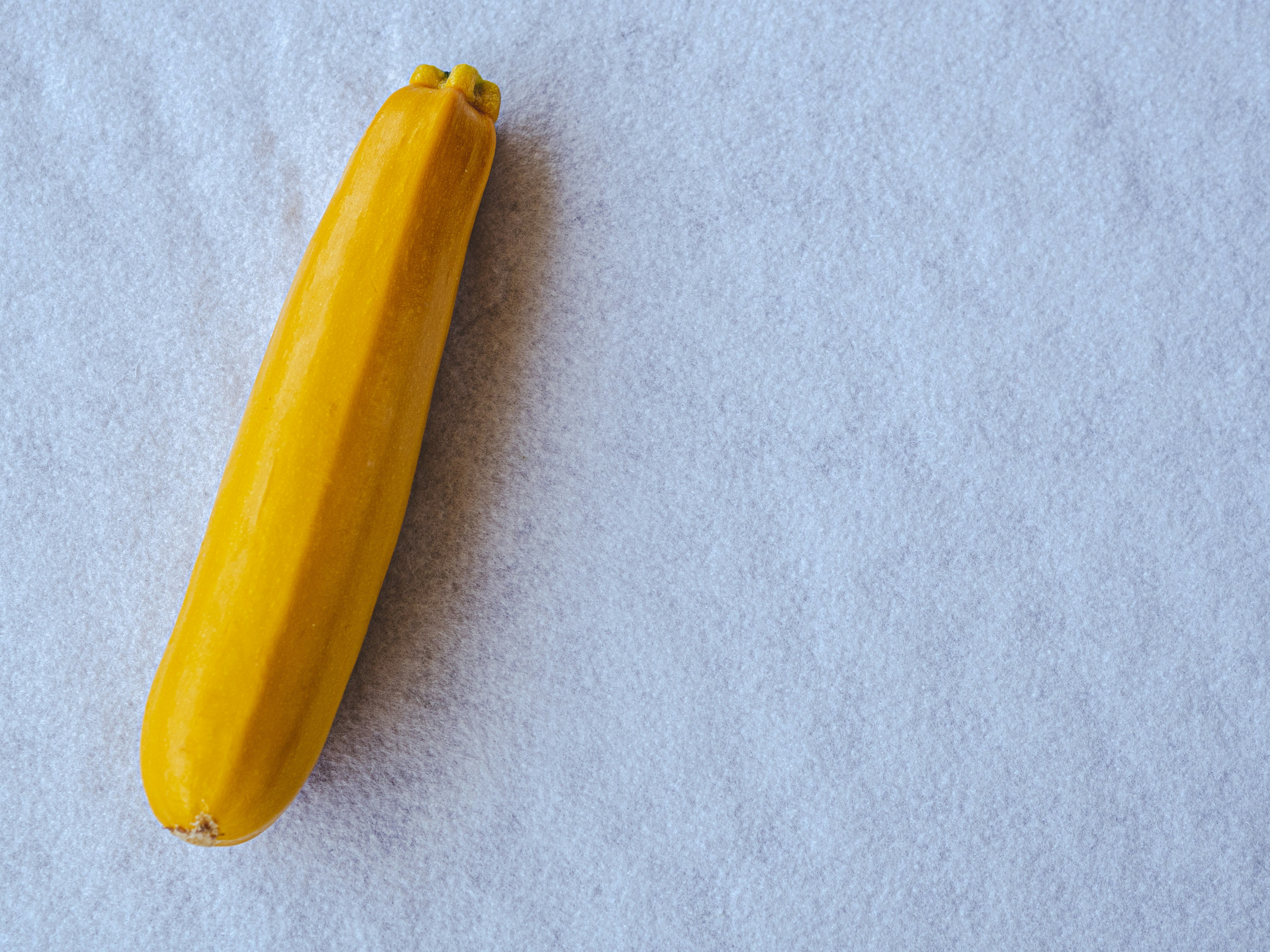 Un calabacín amarillo vibrante colocado sobre un paño blanco