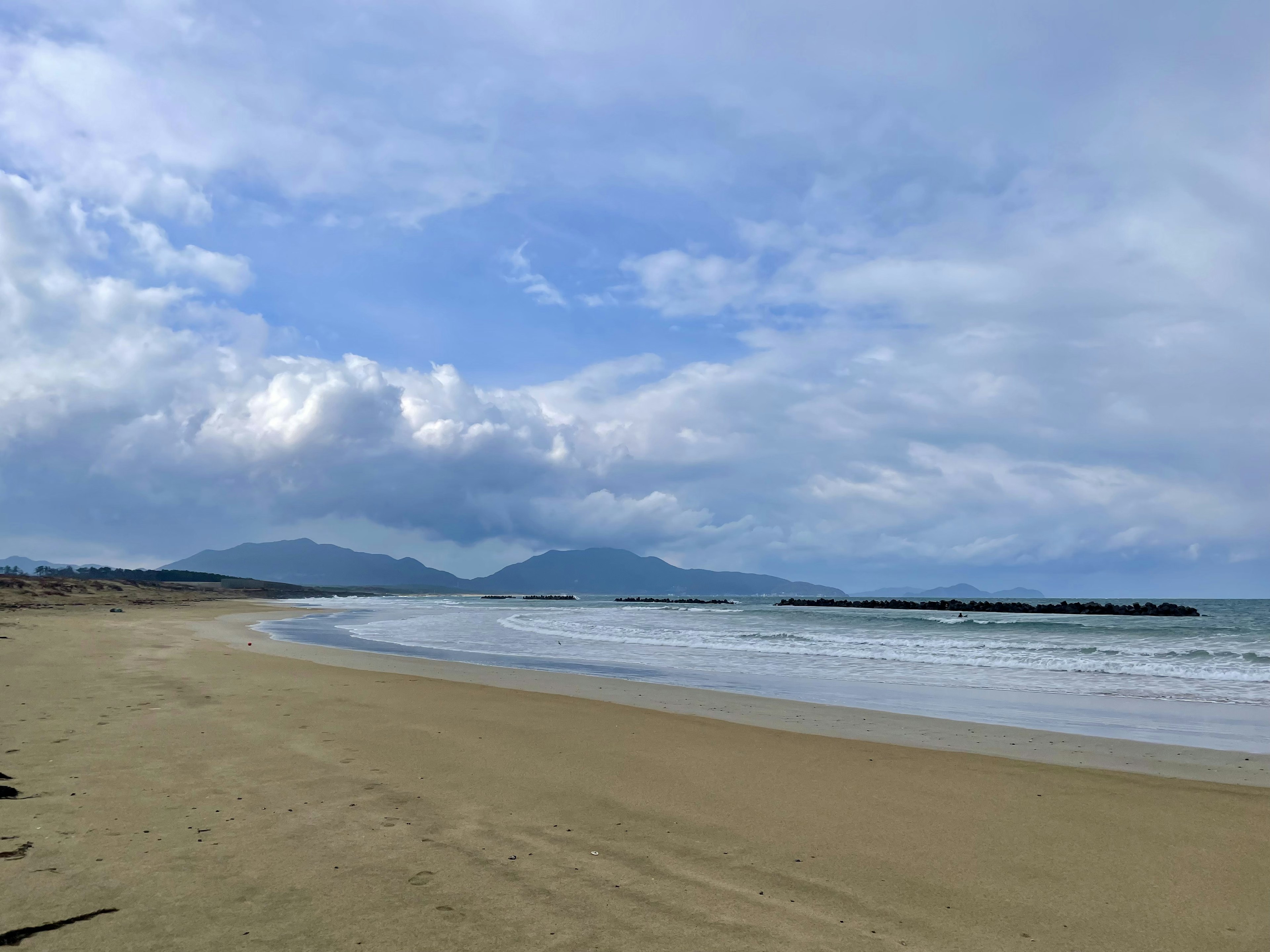 Pemandangan pantai dengan langit biru dan awan garis pantai dan laut bergelombang