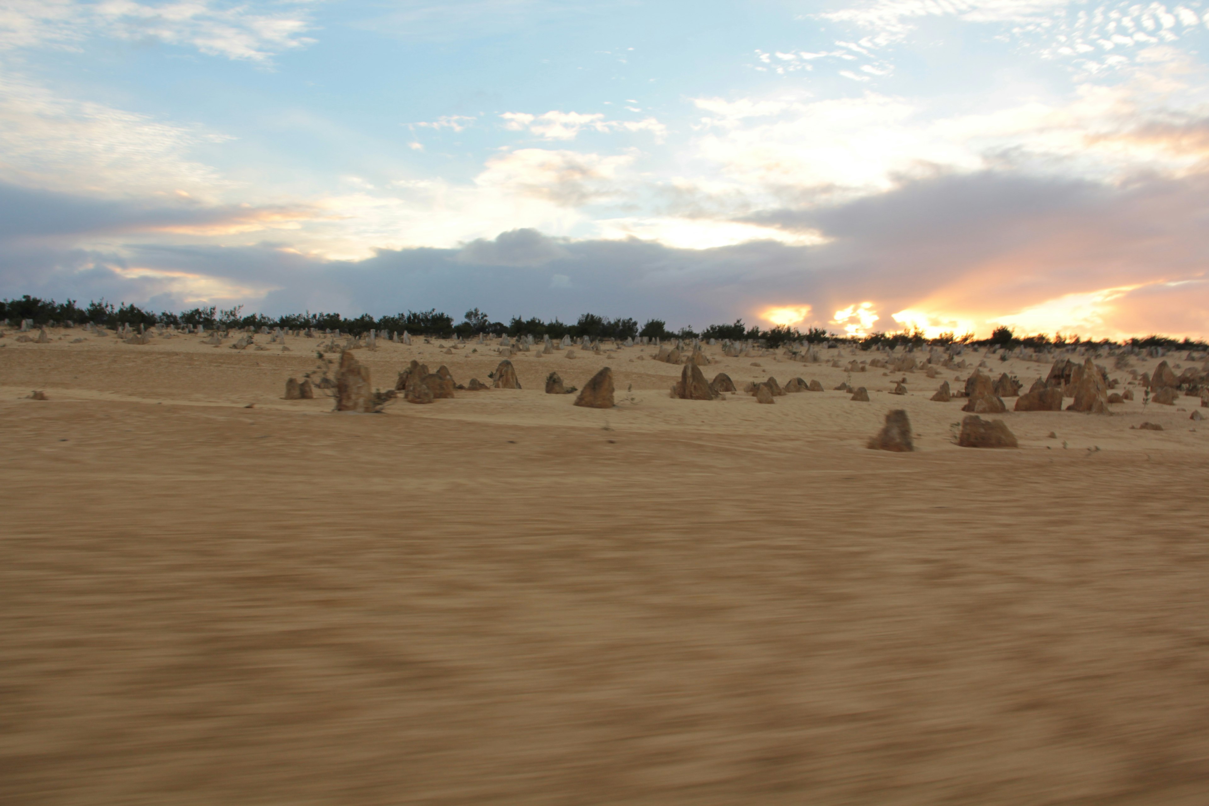 Unique rock formations scattered across a sandy landscape at sunset