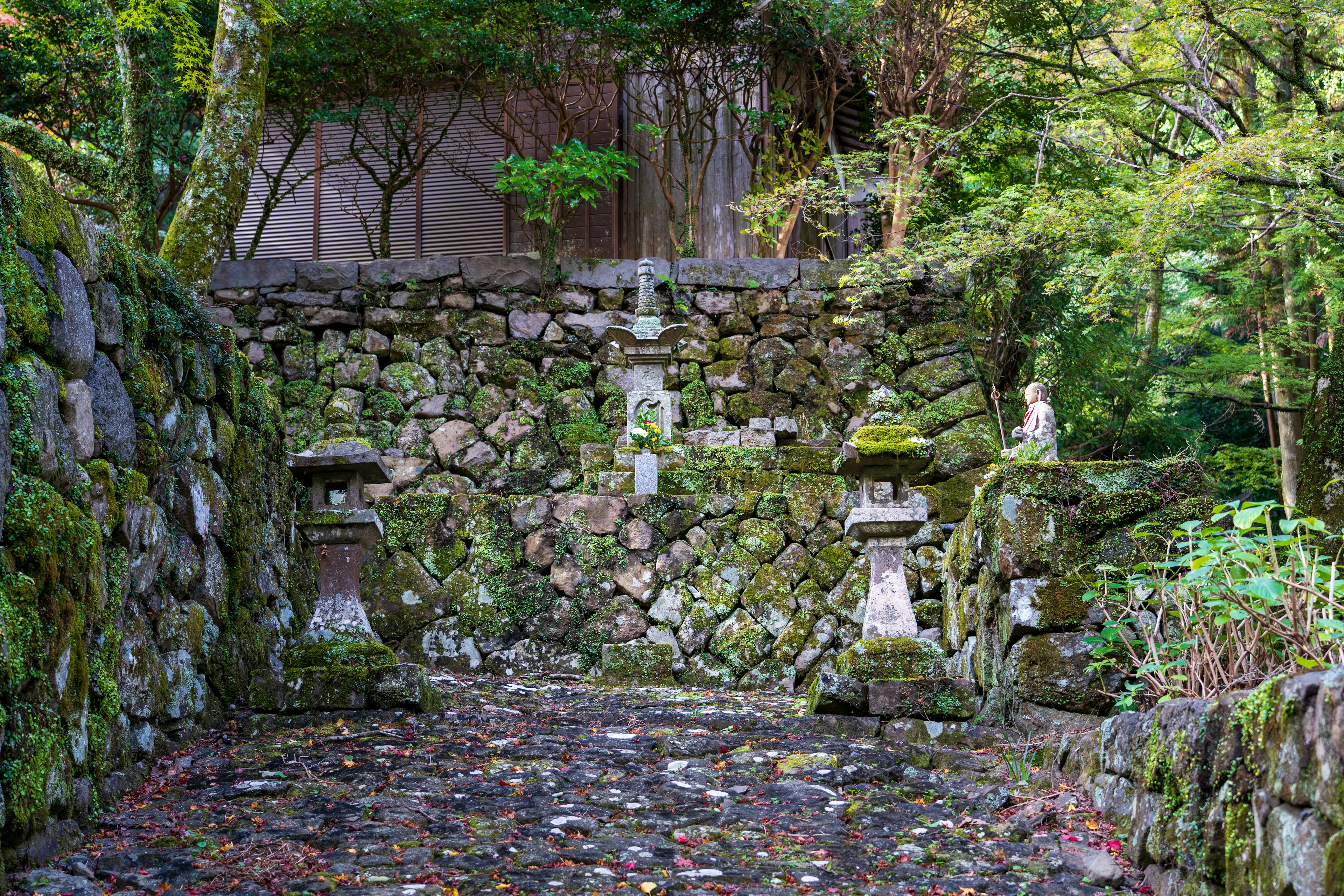 Escena de jardín serena con muros de piedra cubiertos de musgo y faroles de piedra