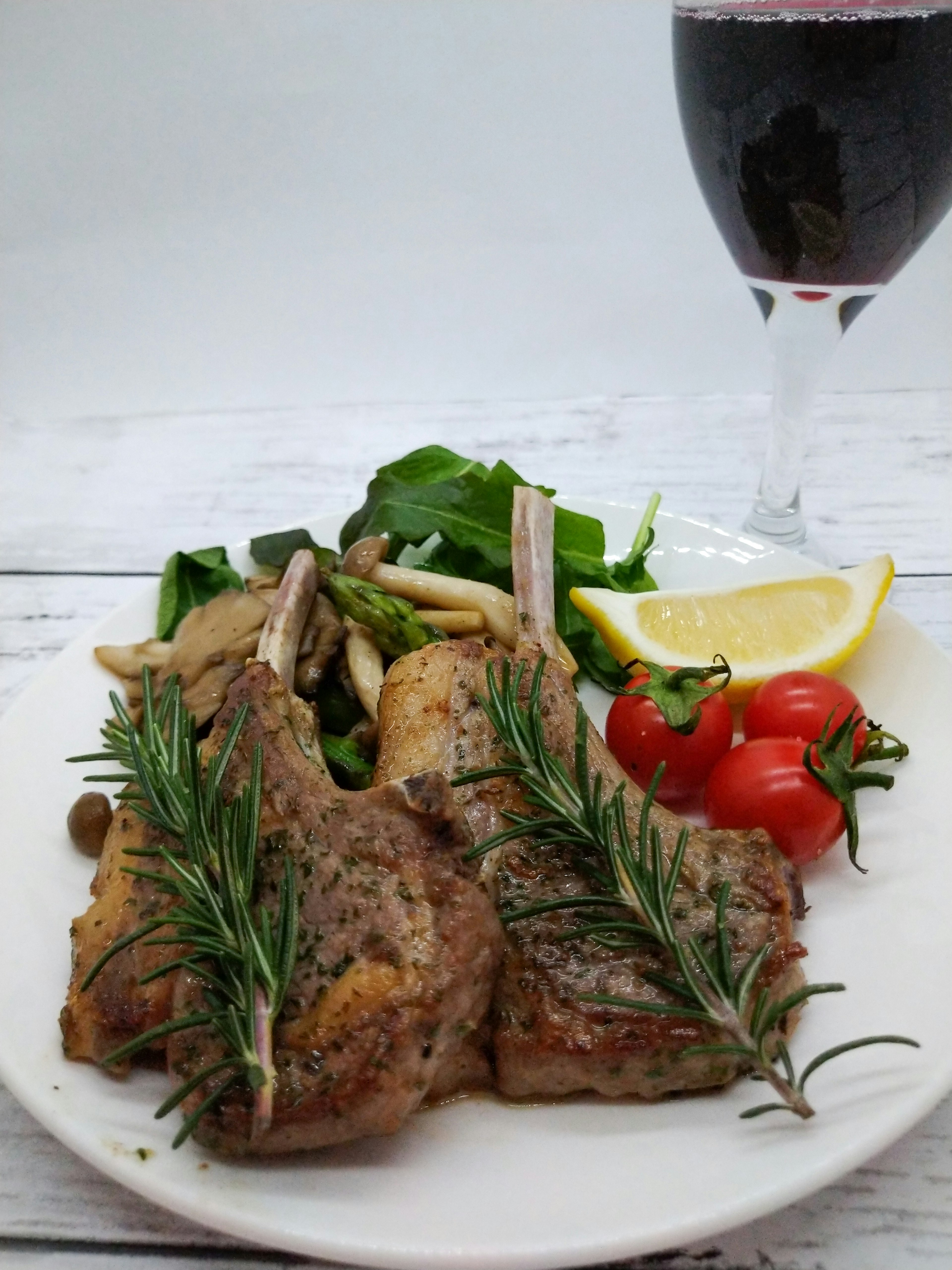 Daging domba yang lezat dihiasi dengan rosemary disajikan dengan salad dan tomat ceri