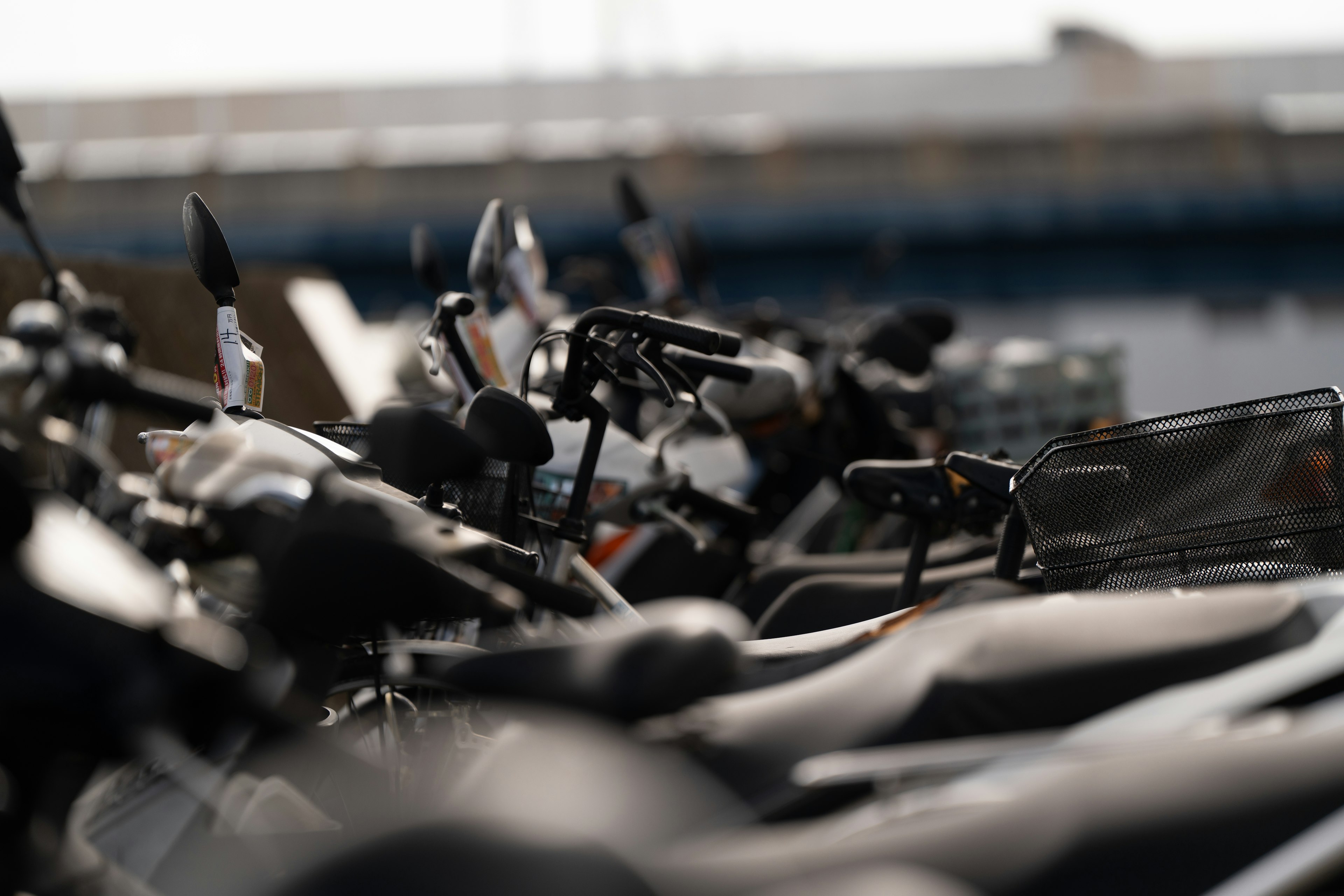 Pemandangan beberapa sepeda motor berjejer di area parkir sepeda motor yang fokus dengan latar belakang buram