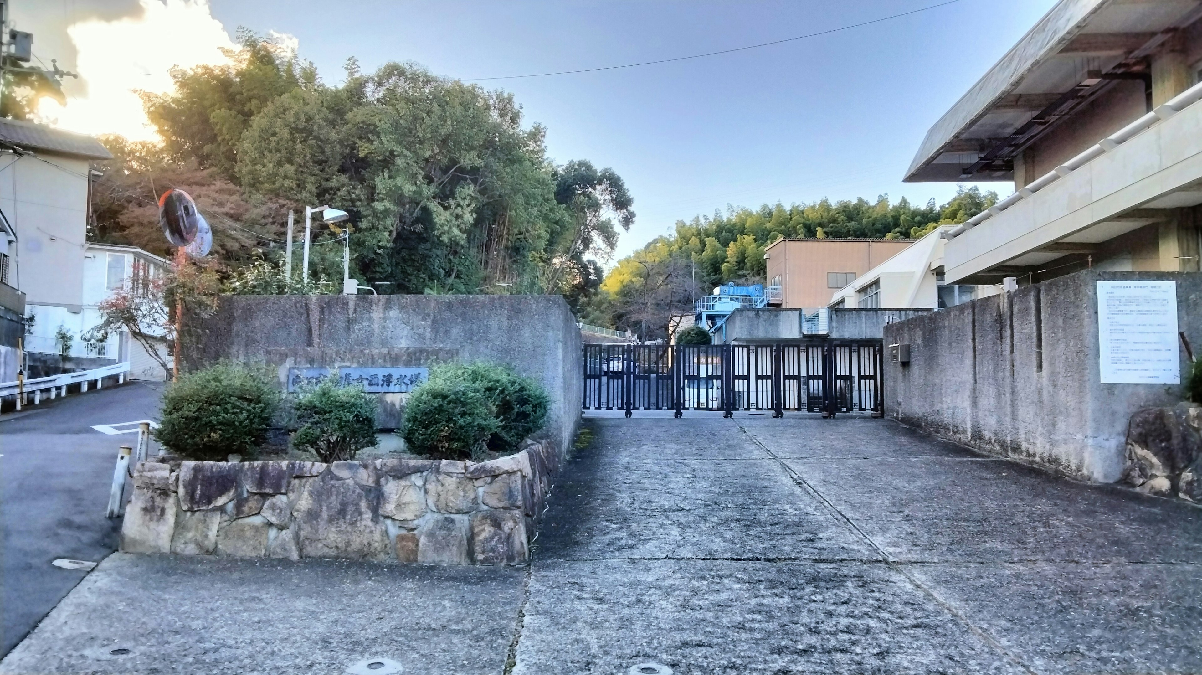 View of a school entrance surrounded by concrete walls green plants and a clear blue sky