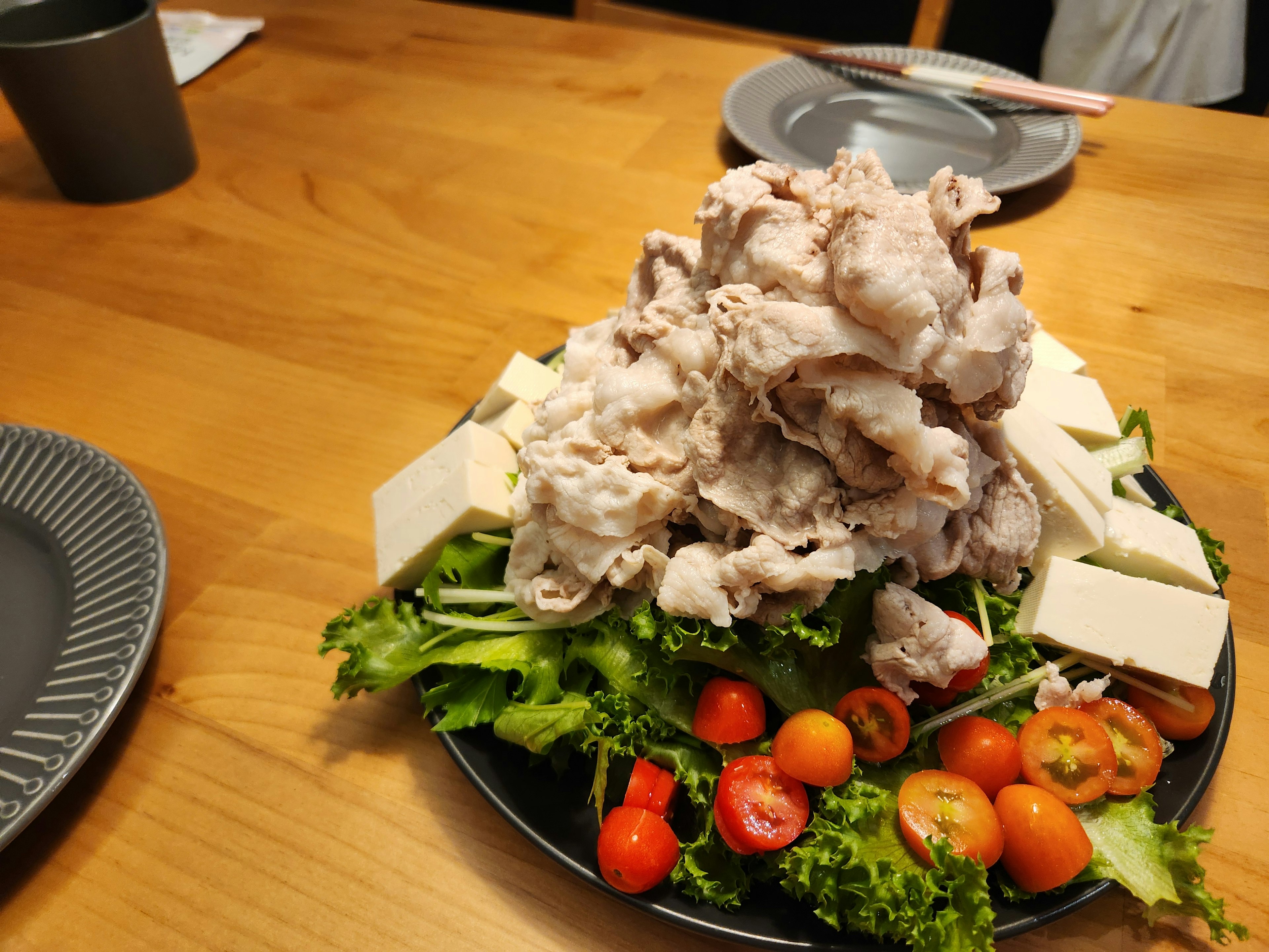 サラダの上に盛り付けられた豚肉と豆腐の料理