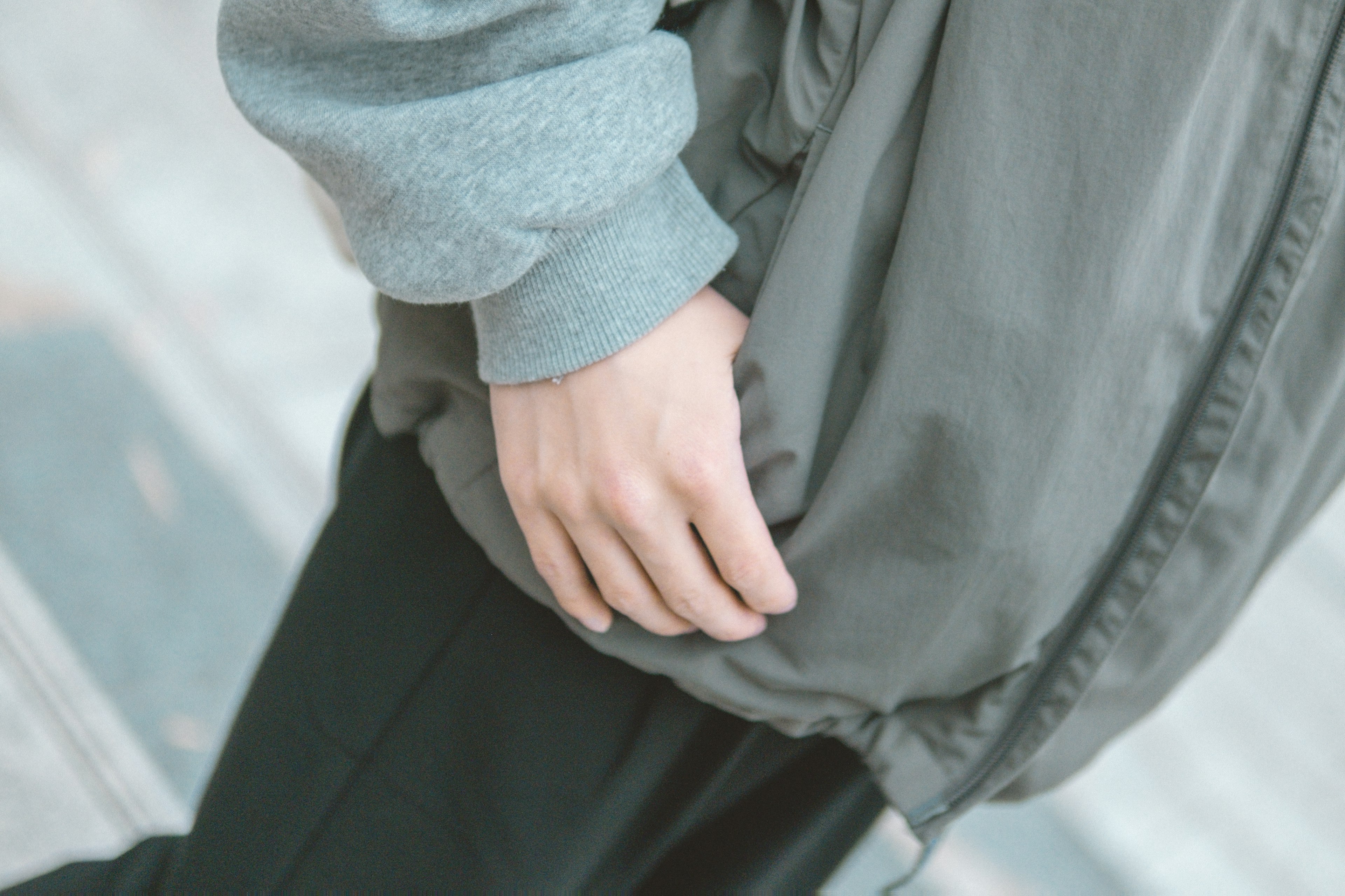 A person's hand in a pocket of a gray jacket