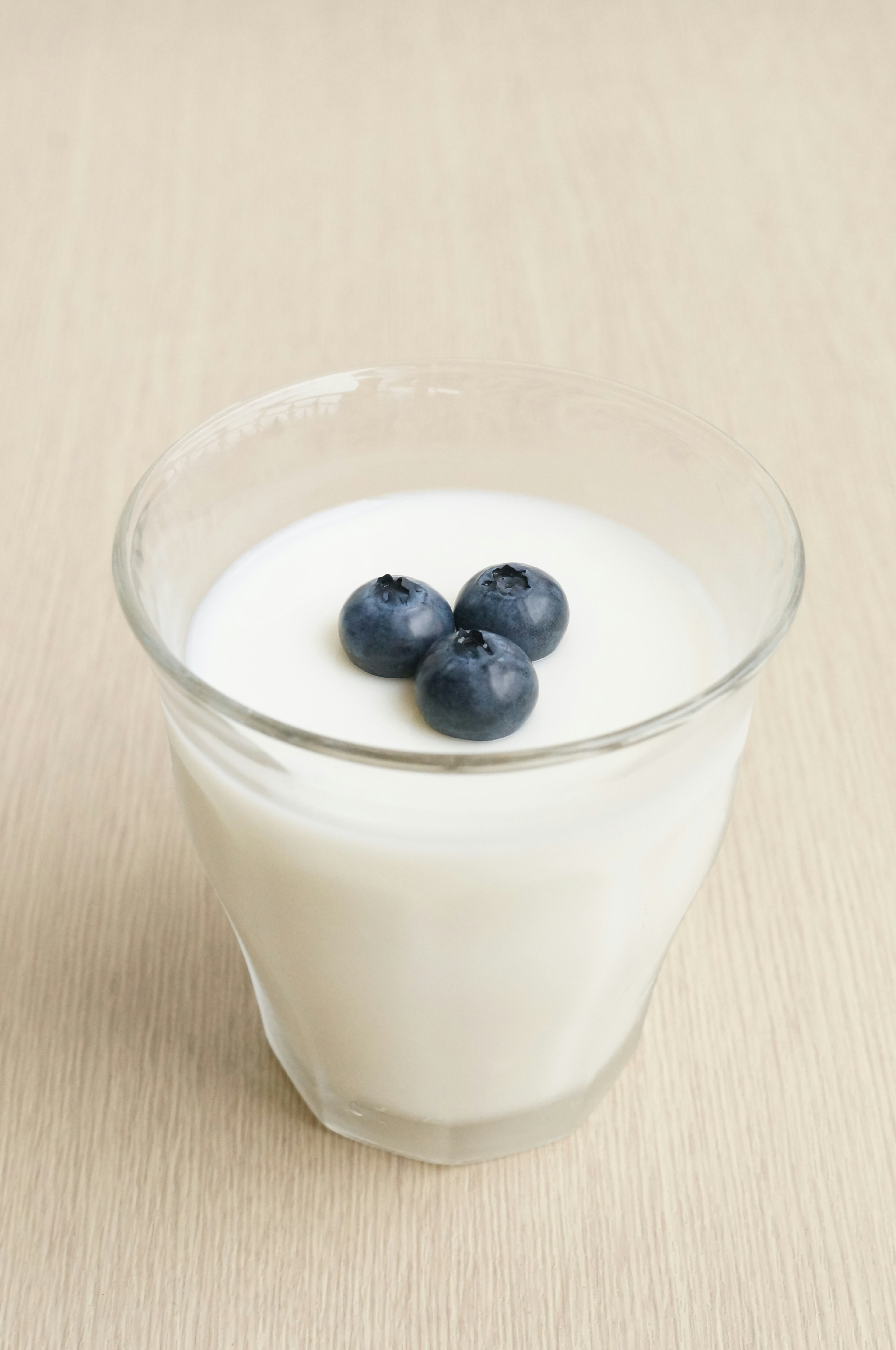 Transparent glass with yogurt topped by three blueberries