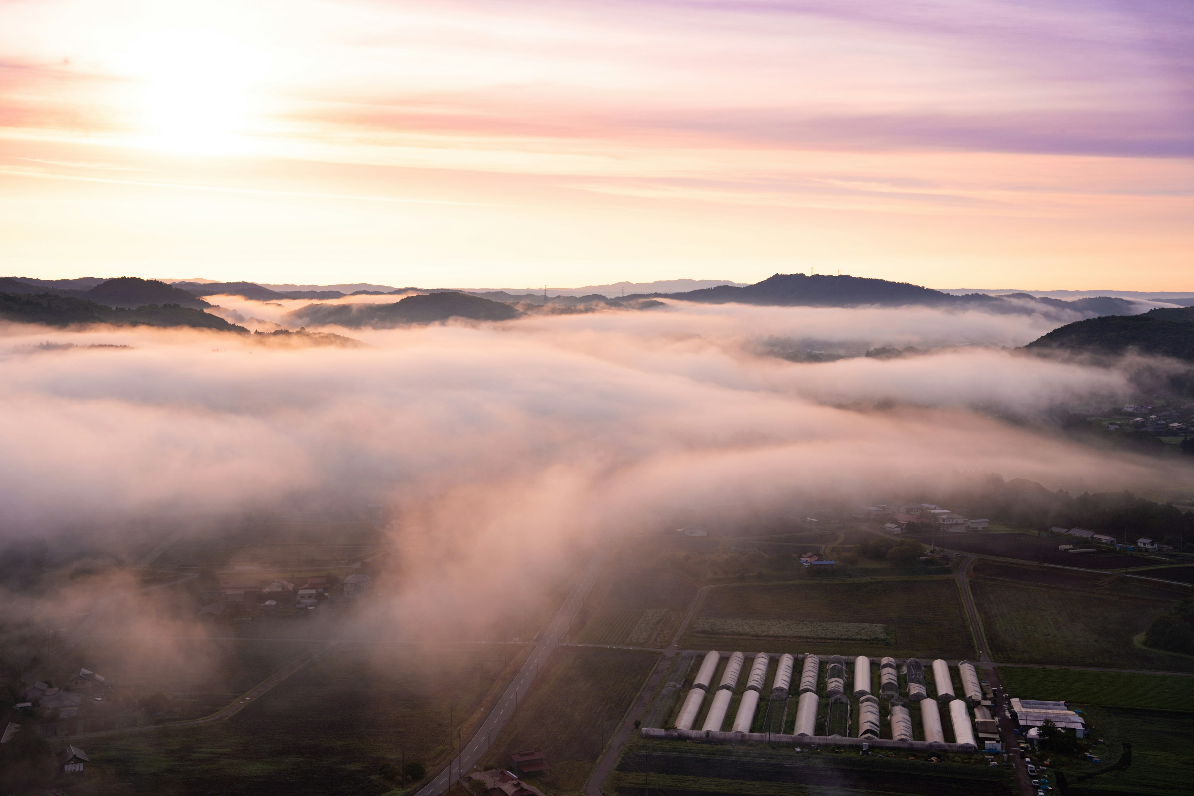 Sonnenlicht, das eine von Nebel bedeckte Landschaft mit entfernten Hügeln beleuchtet