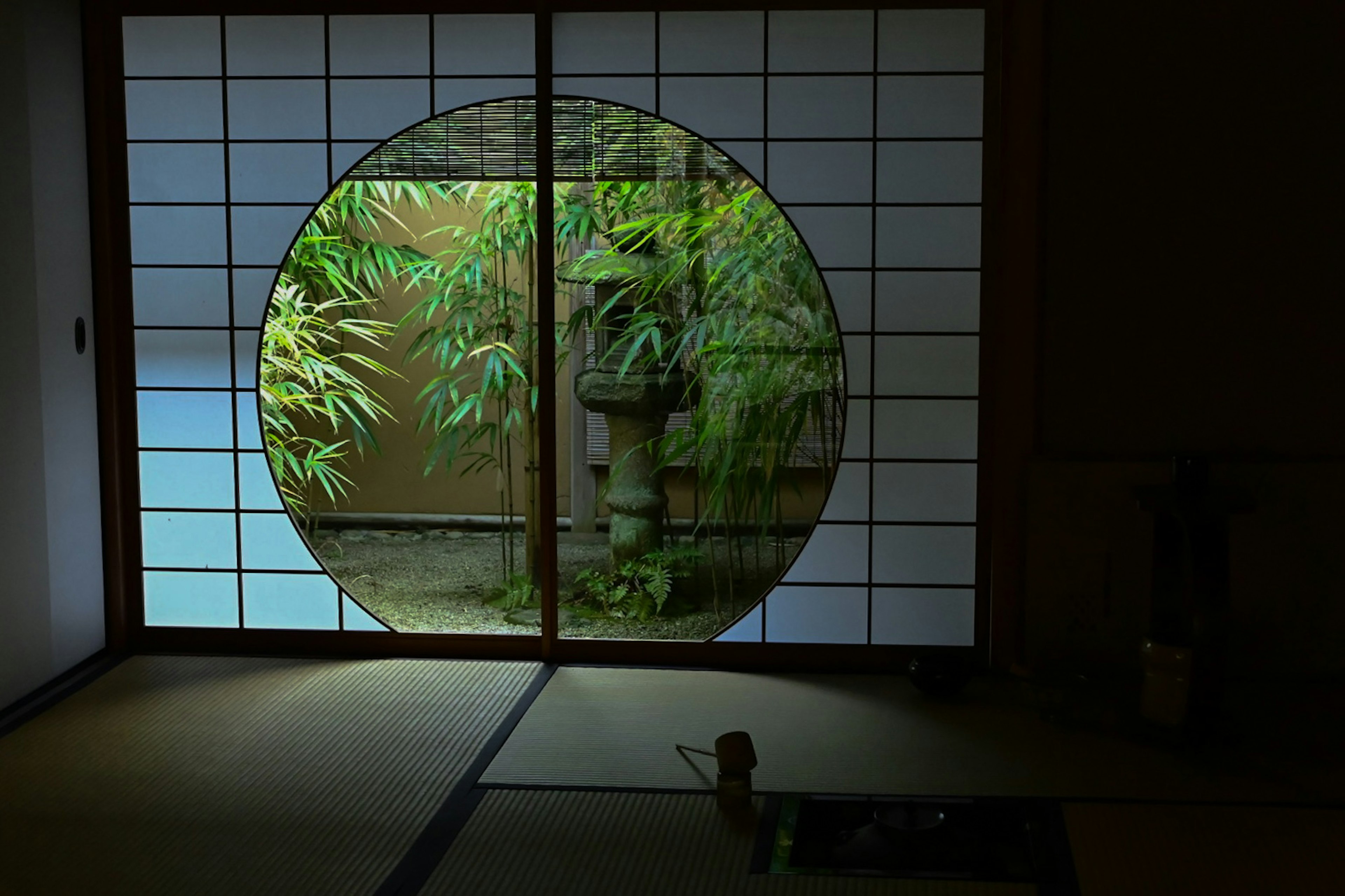 Fenêtre ronde montrant une vue de bambou avec intérieur japonais traditionnel