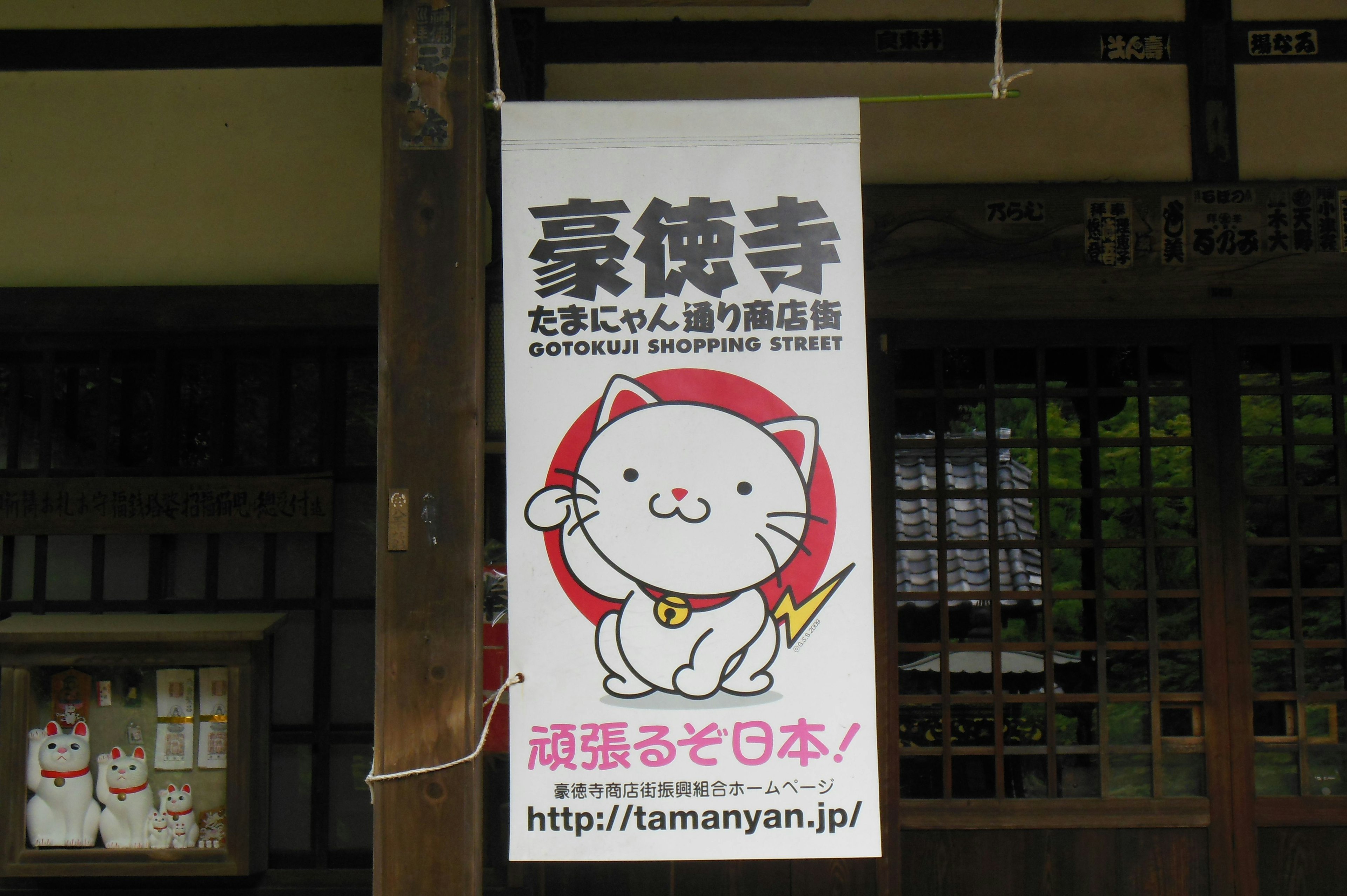 Panneau présentant un personnage de chat mignon du temple Gotokuji avec une URL de site web