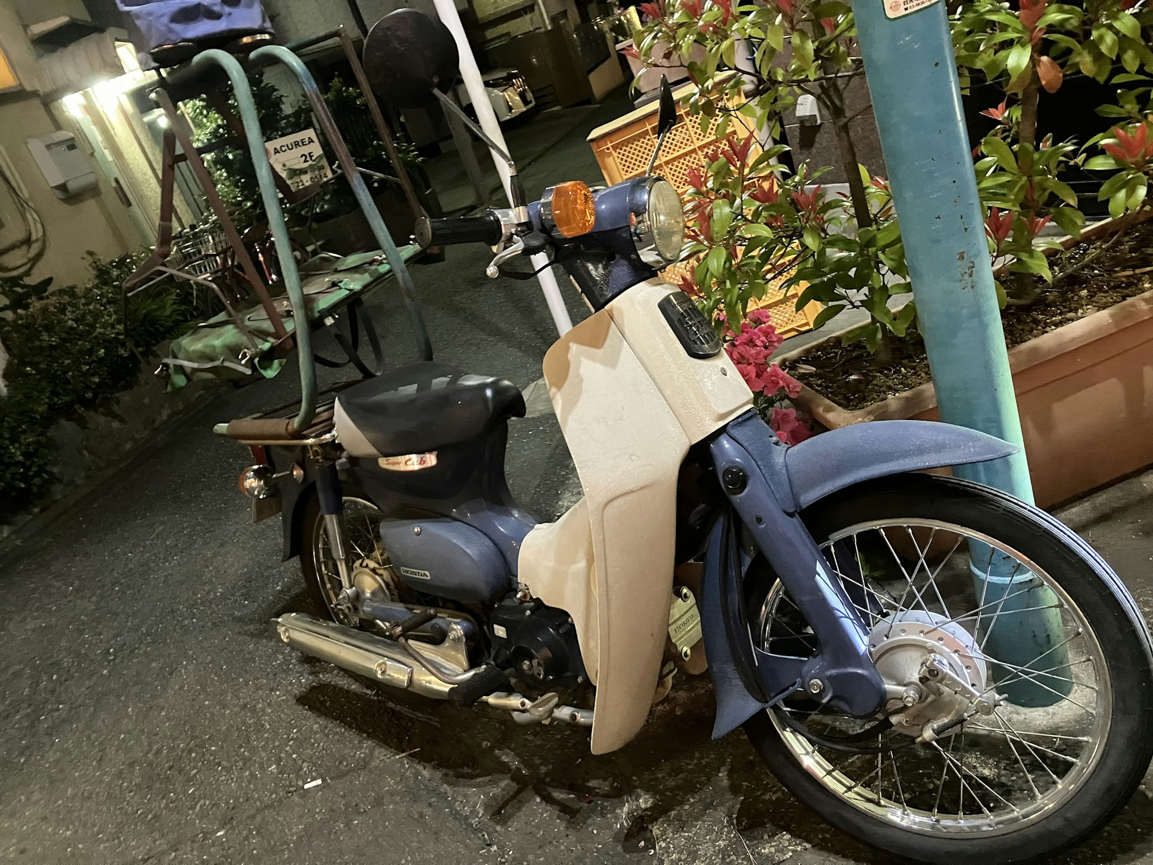 A blue motorcycle with a white front fairing parked in a nighttime setting