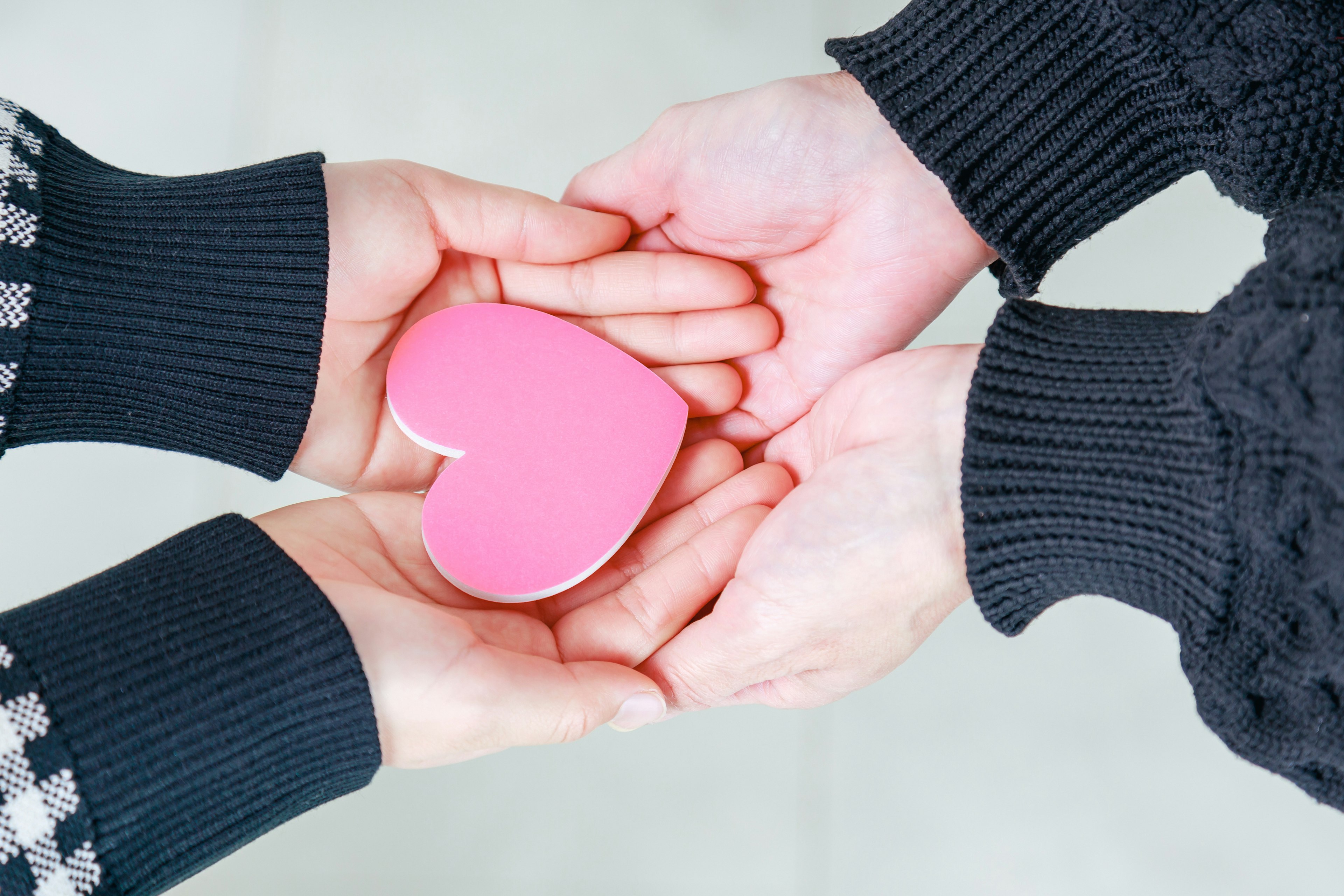 Dos manos sosteniendo un objeto en forma de corazón rosa