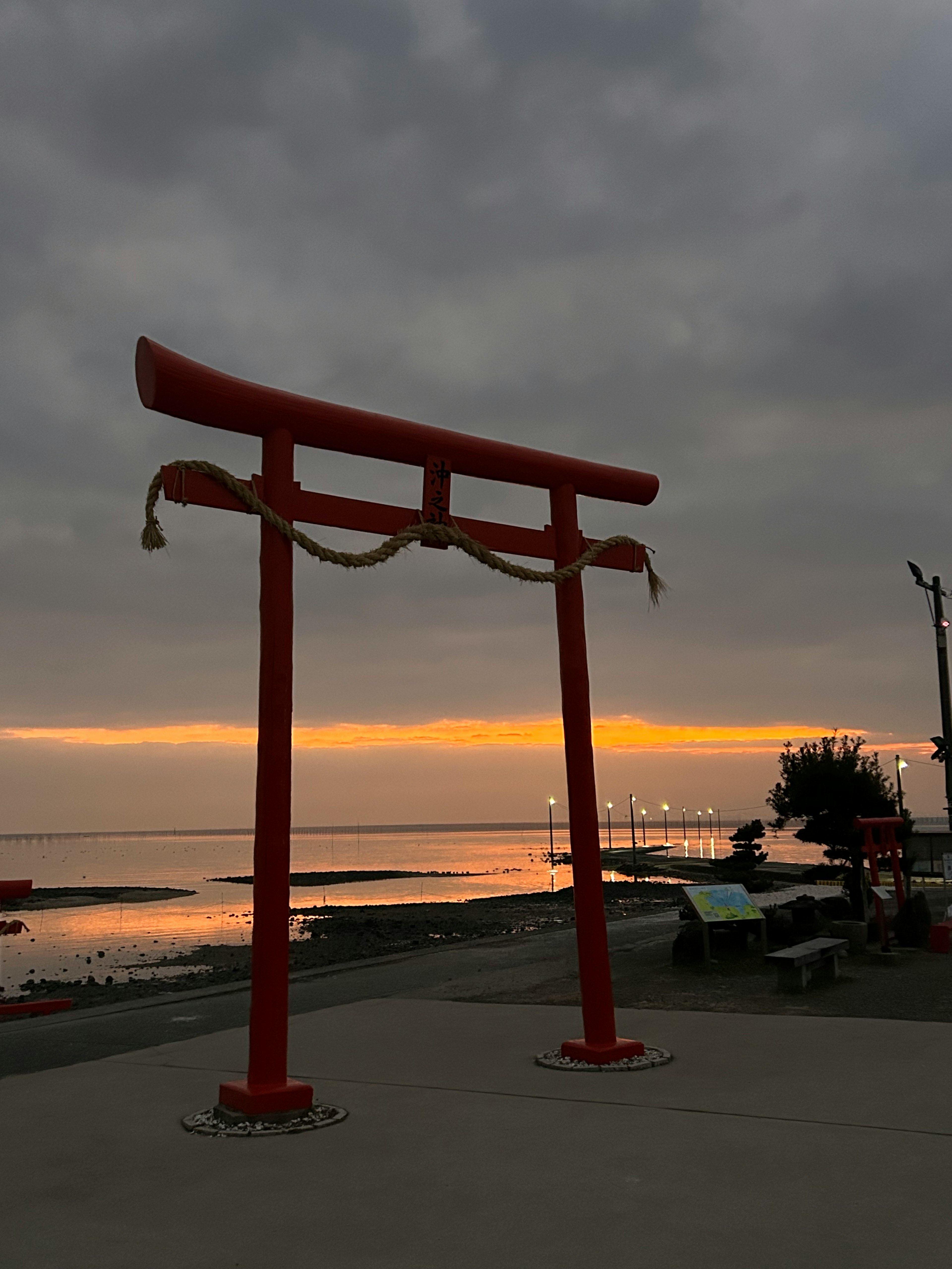 Rotes Torii am Strand mit Sonnenuntergang im Hintergrund