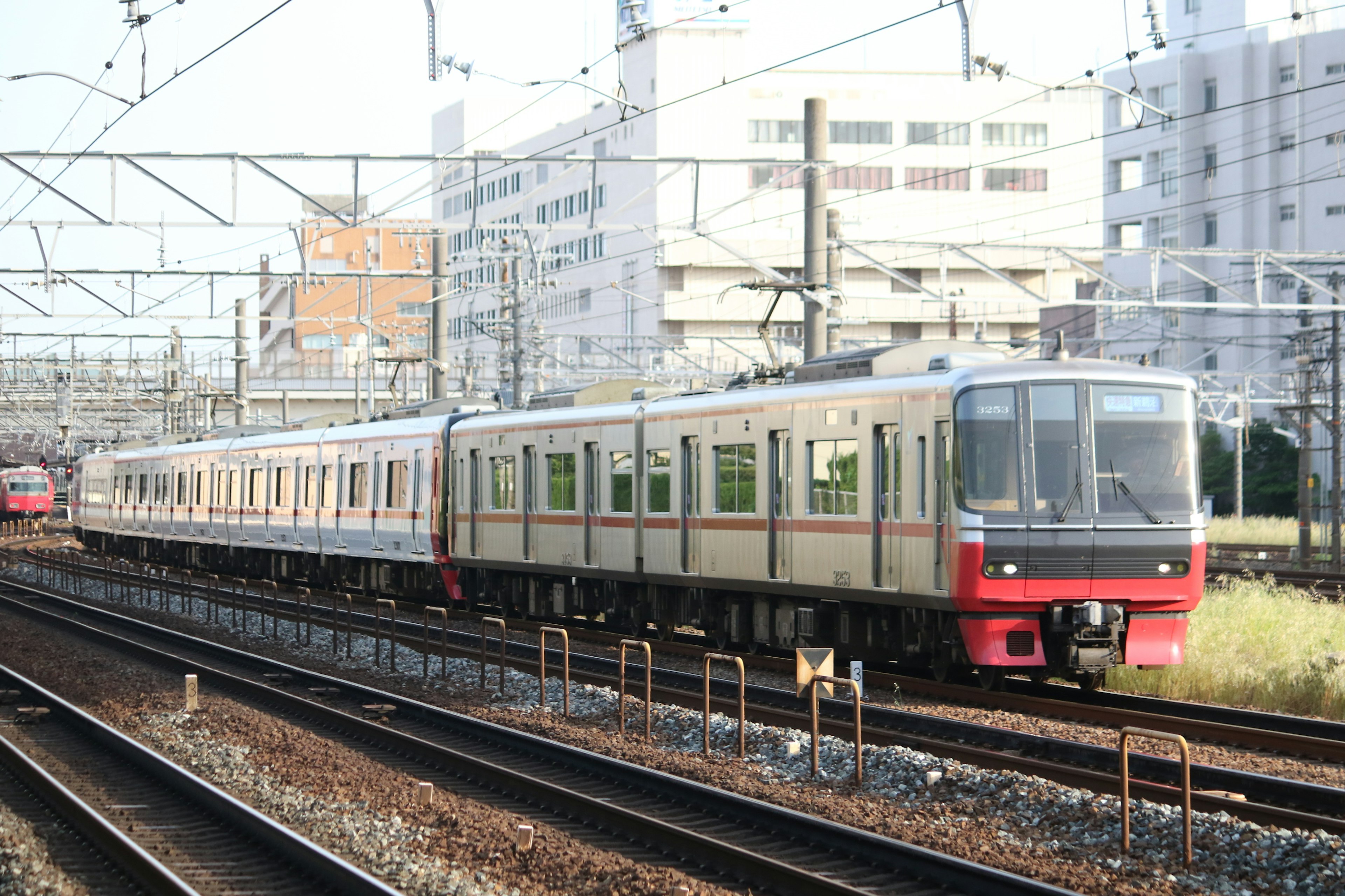 Silver train running on tracks with high-rise buildings in the background